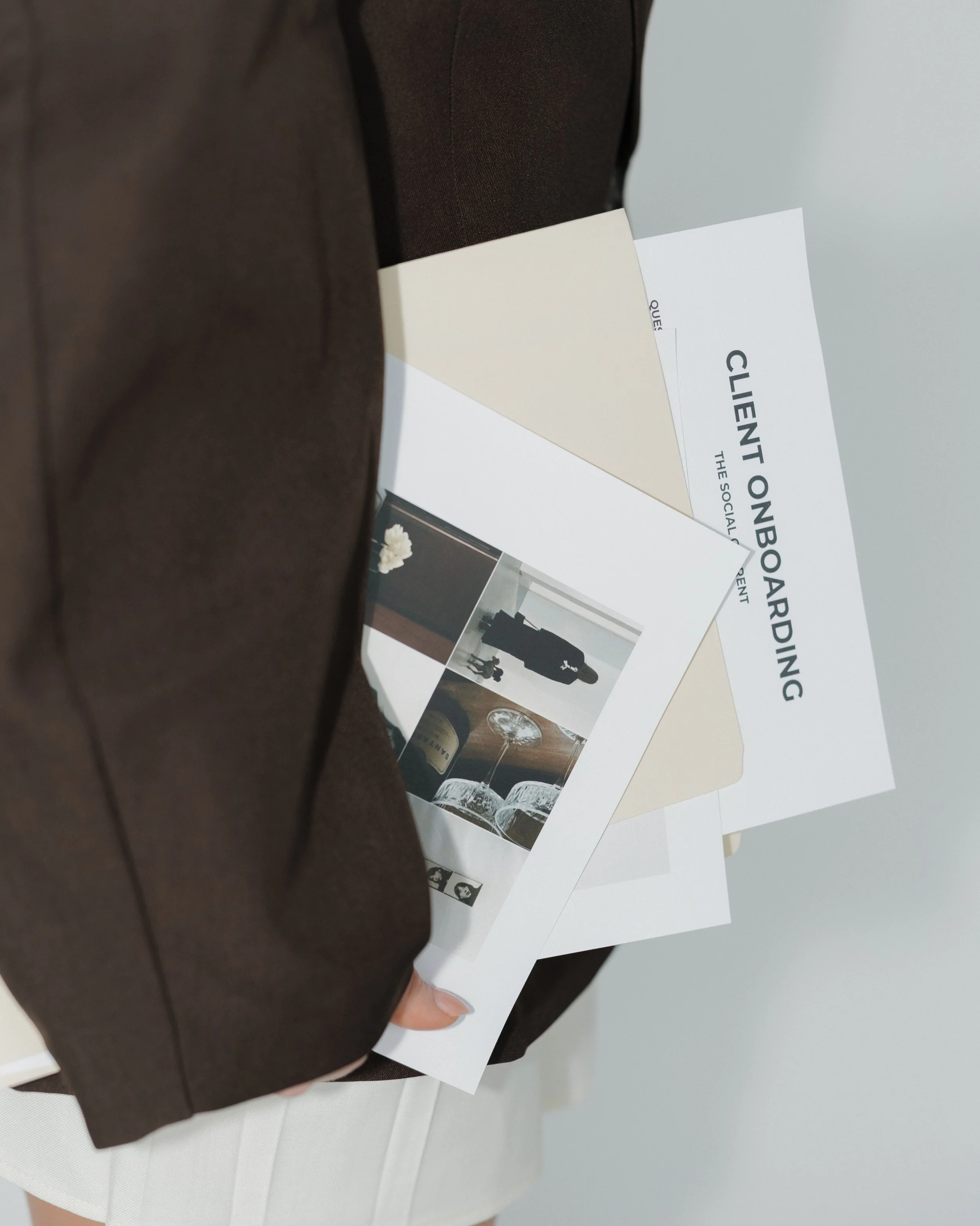 A person holding a brochure and some papers, including a 'Client Onboarding' document.