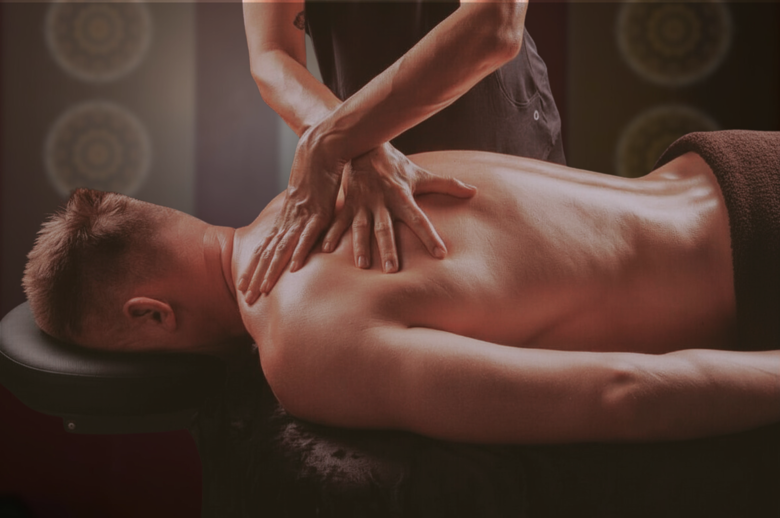 A man receiving a back massage while lying face down on a massage table in a spa or wellness center.