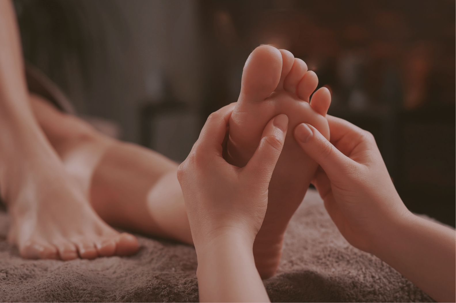 Person receiving a foot massage, lying face down on a massage table.
