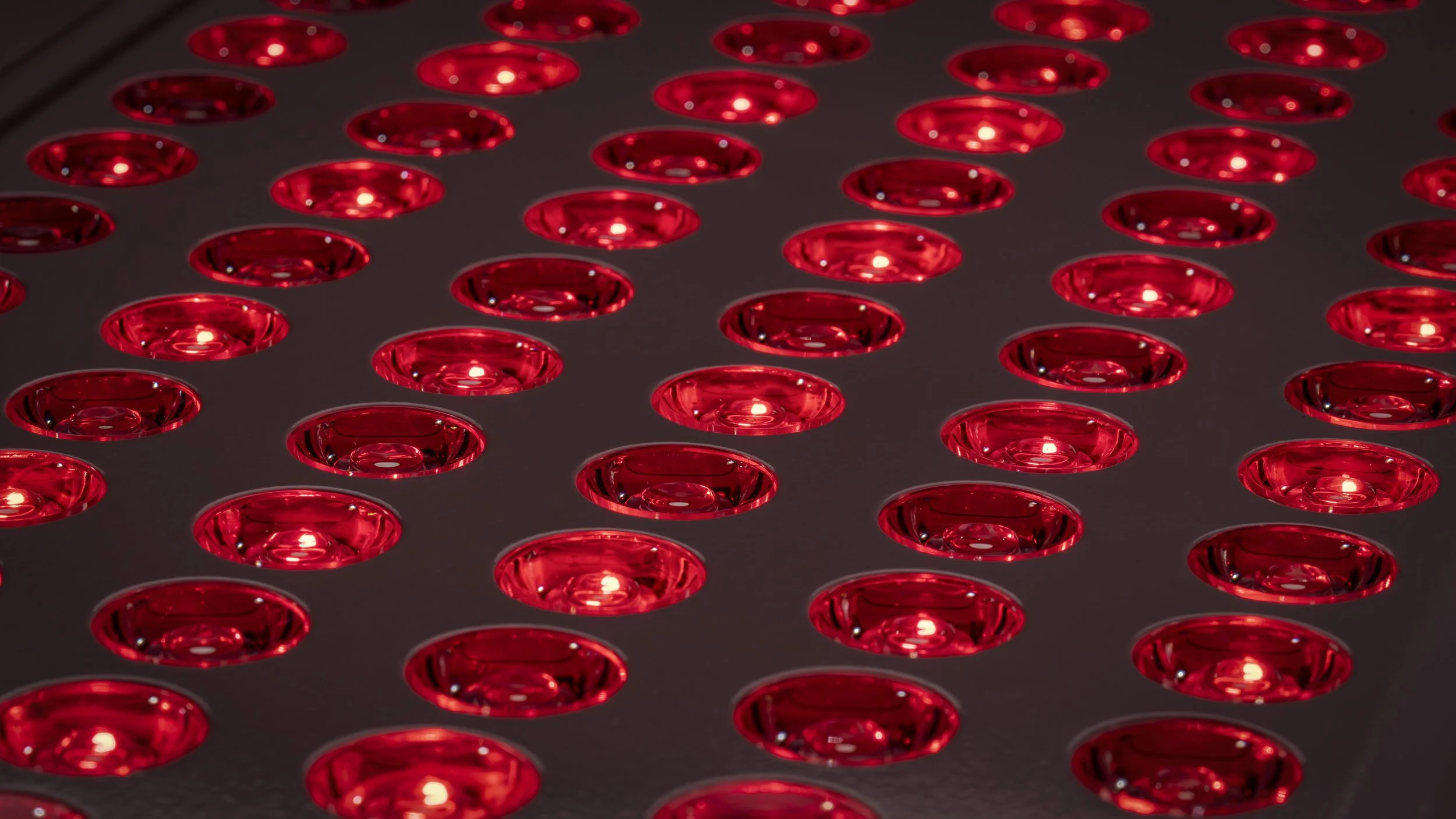 Close-up of Red Light Therapy lights arranged in a grid pattern with a dark background.