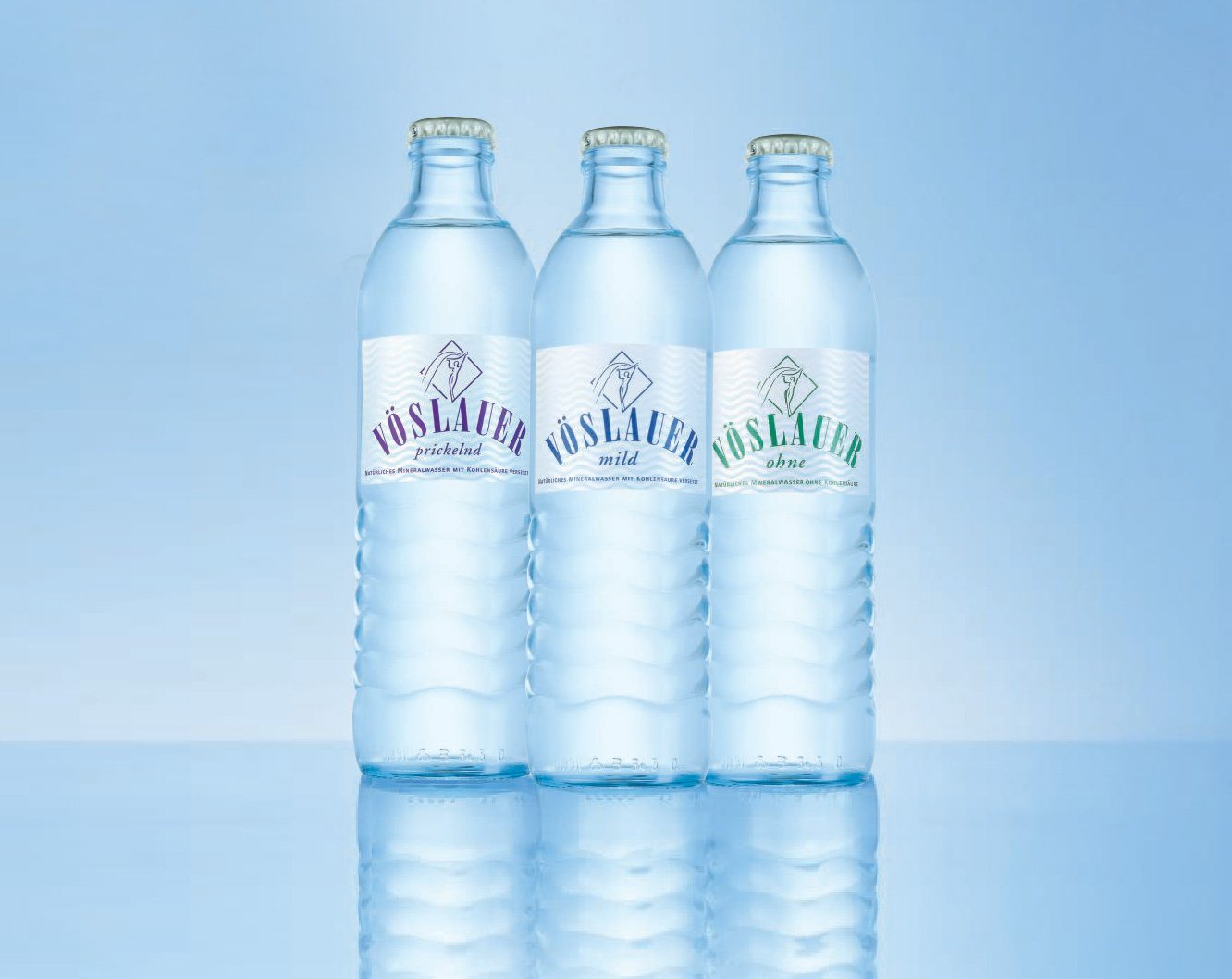 Three bottles of Vöslauer mineral water with labels indicating sparkling, mild, and without carbonation, set against a light blue background.