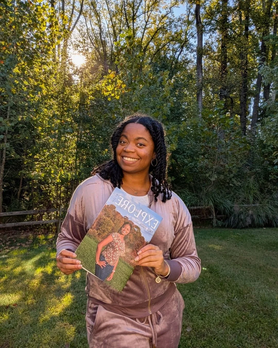 Black woman smiling in yard with Explore by Lexi fall magazine.