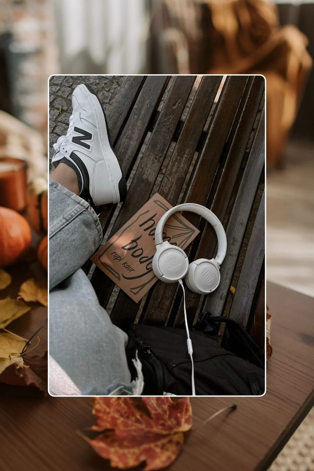 Someone sitting on a bench next to a book and headphones