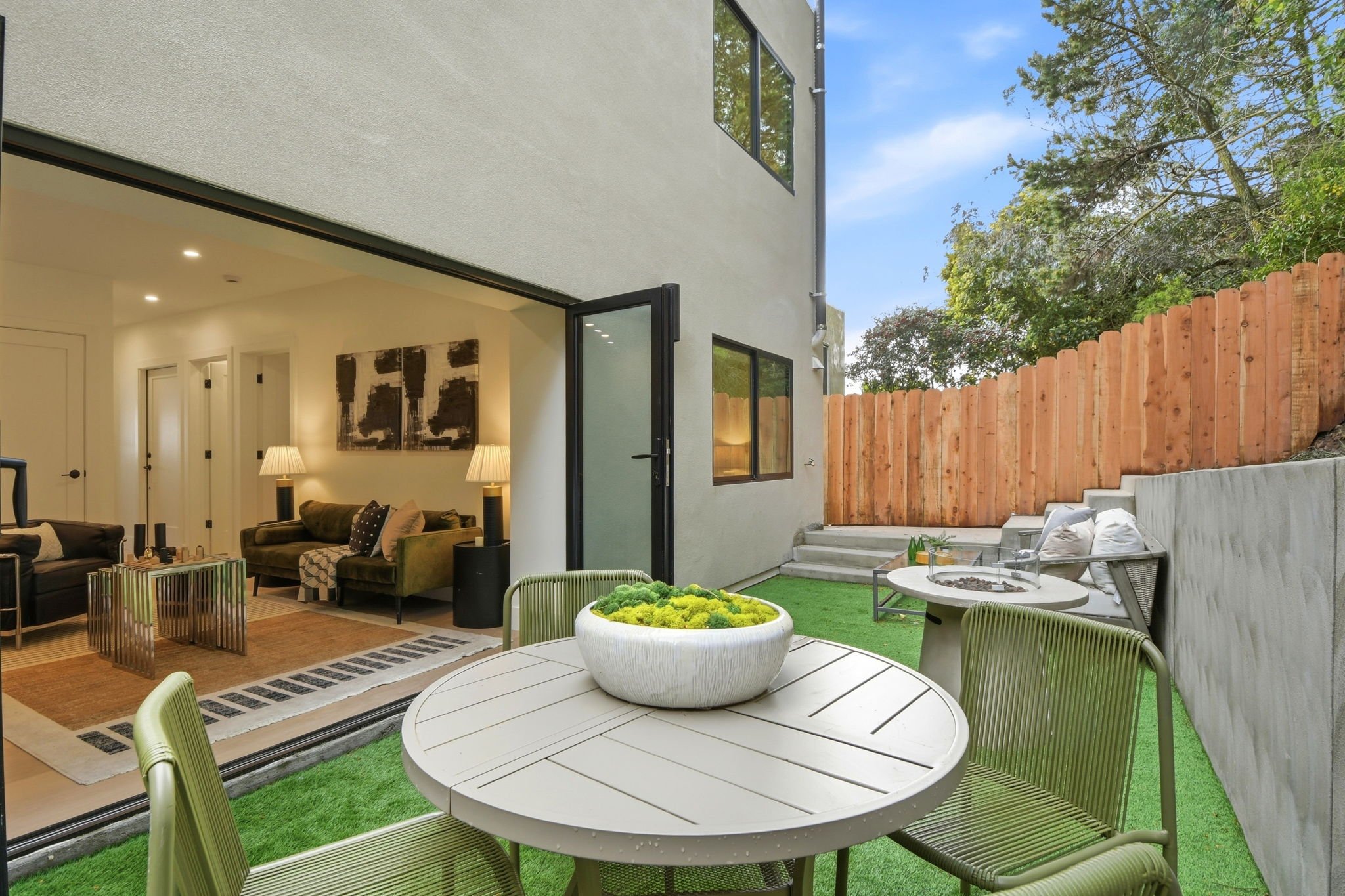 Exterior view of a luxury Midtown Terrace residence showing the private backyard and bifold doors opening to a modern interior lounge.