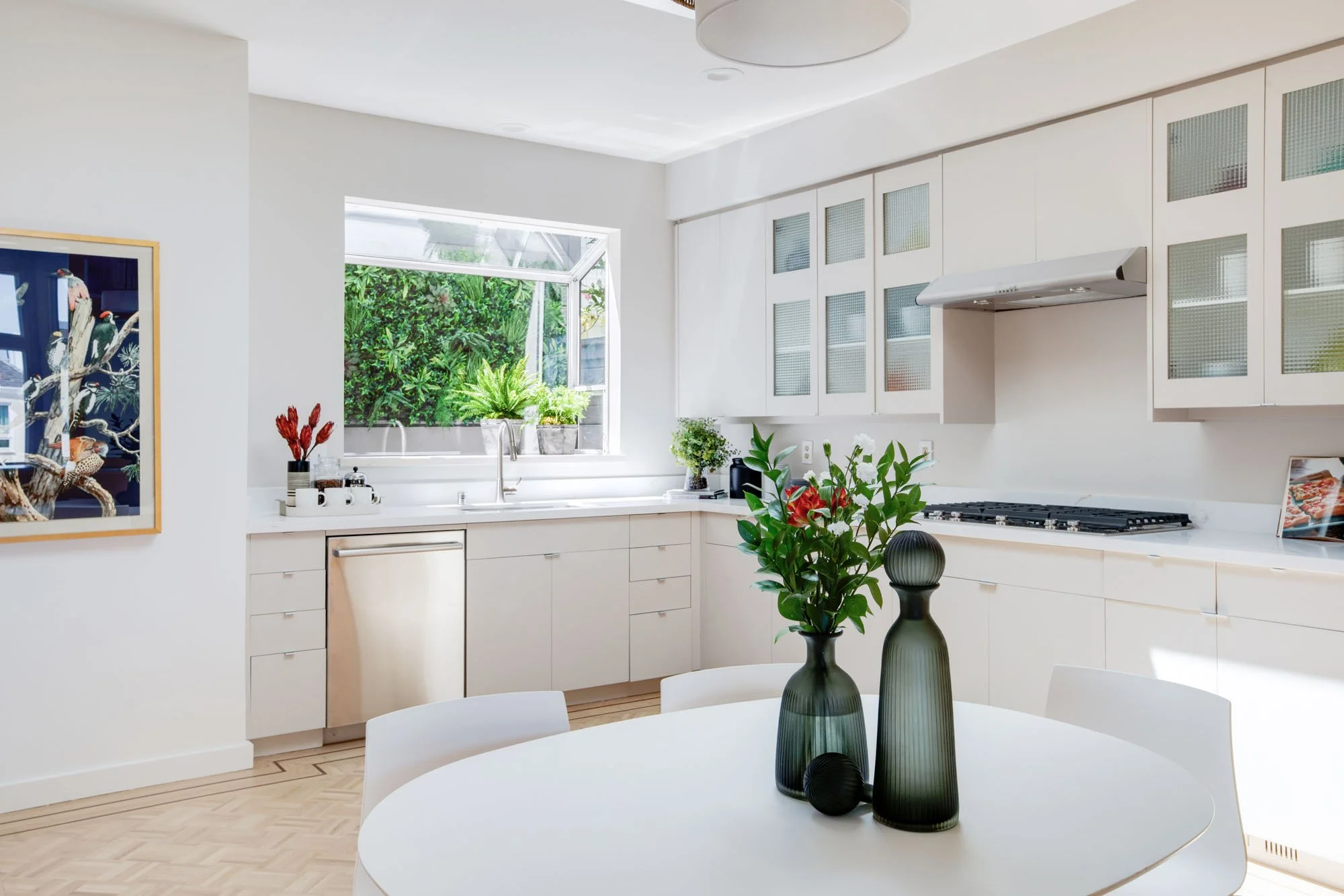 Designer kitchen in San Francisco with white quartz countertops, glass-front upper cabinets, and a professional gas range under a minimalist hood.