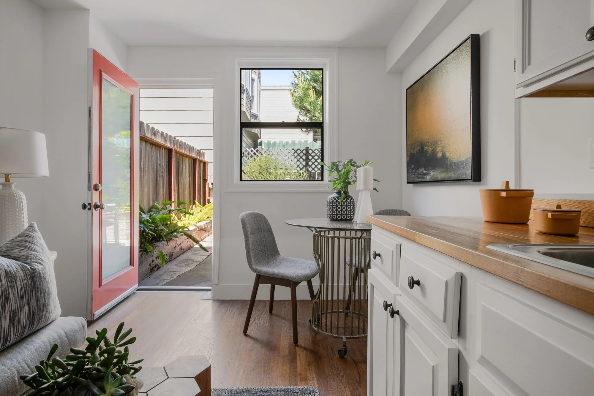 View of the light-filled lower living space at 2872 25th Street, showing the indoor-outdoor flow through a vibrant red glass-paneled door.