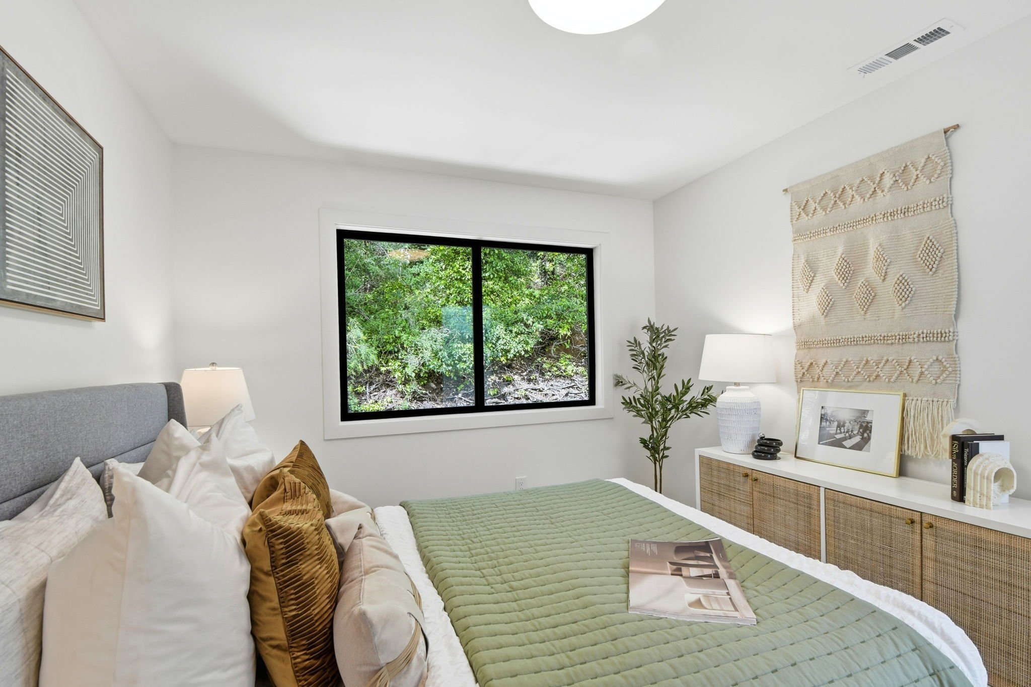 Sophisticated bedroom interior featuring a textured wall hanging, light wood flooring, and contemporary furnishings in a renovated SF home.