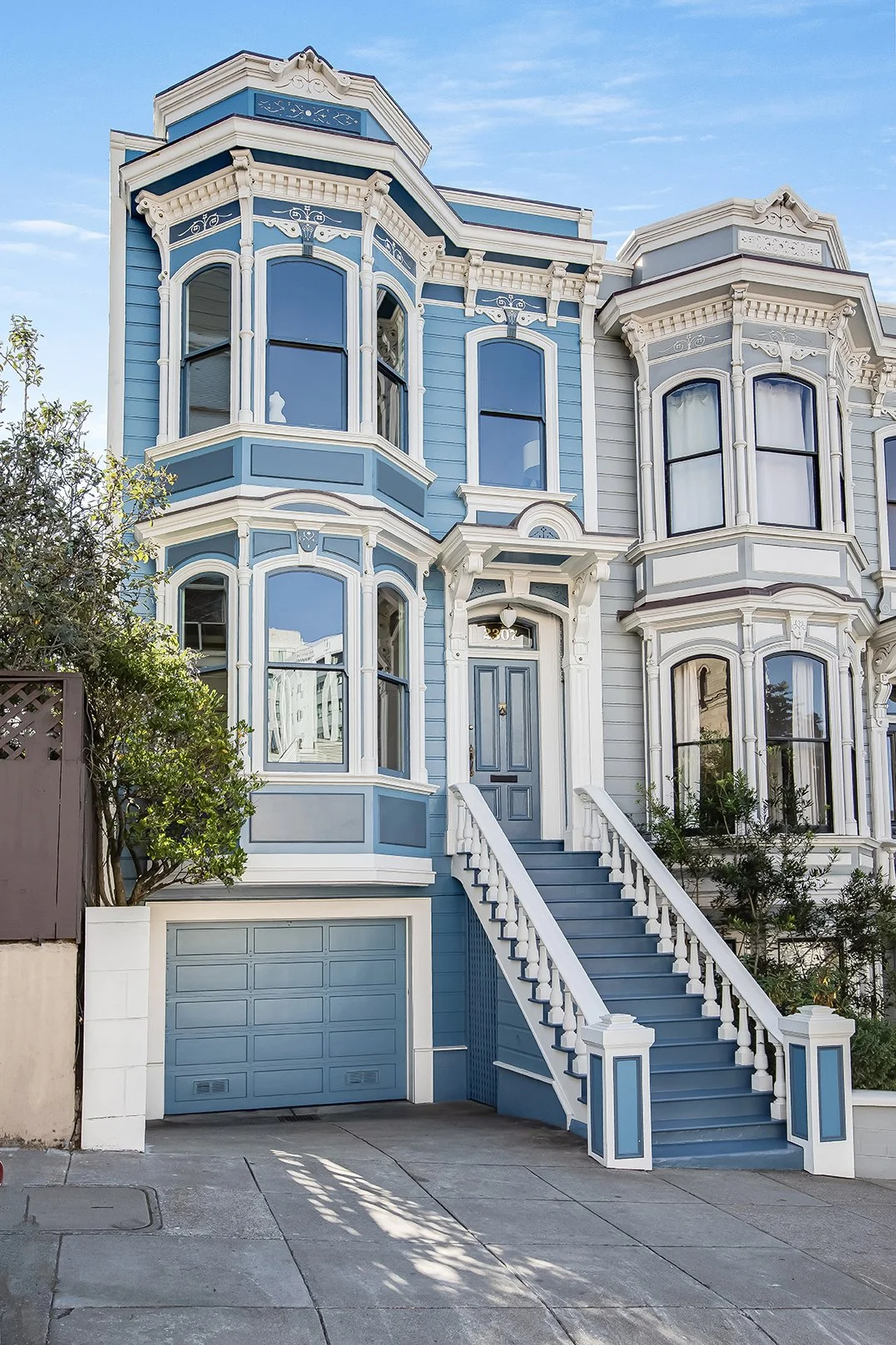 Full exterior view of a classic blue Victorian residence in San Francisco’s Pacific Heights, featuring ornate period trim and a private garage.
