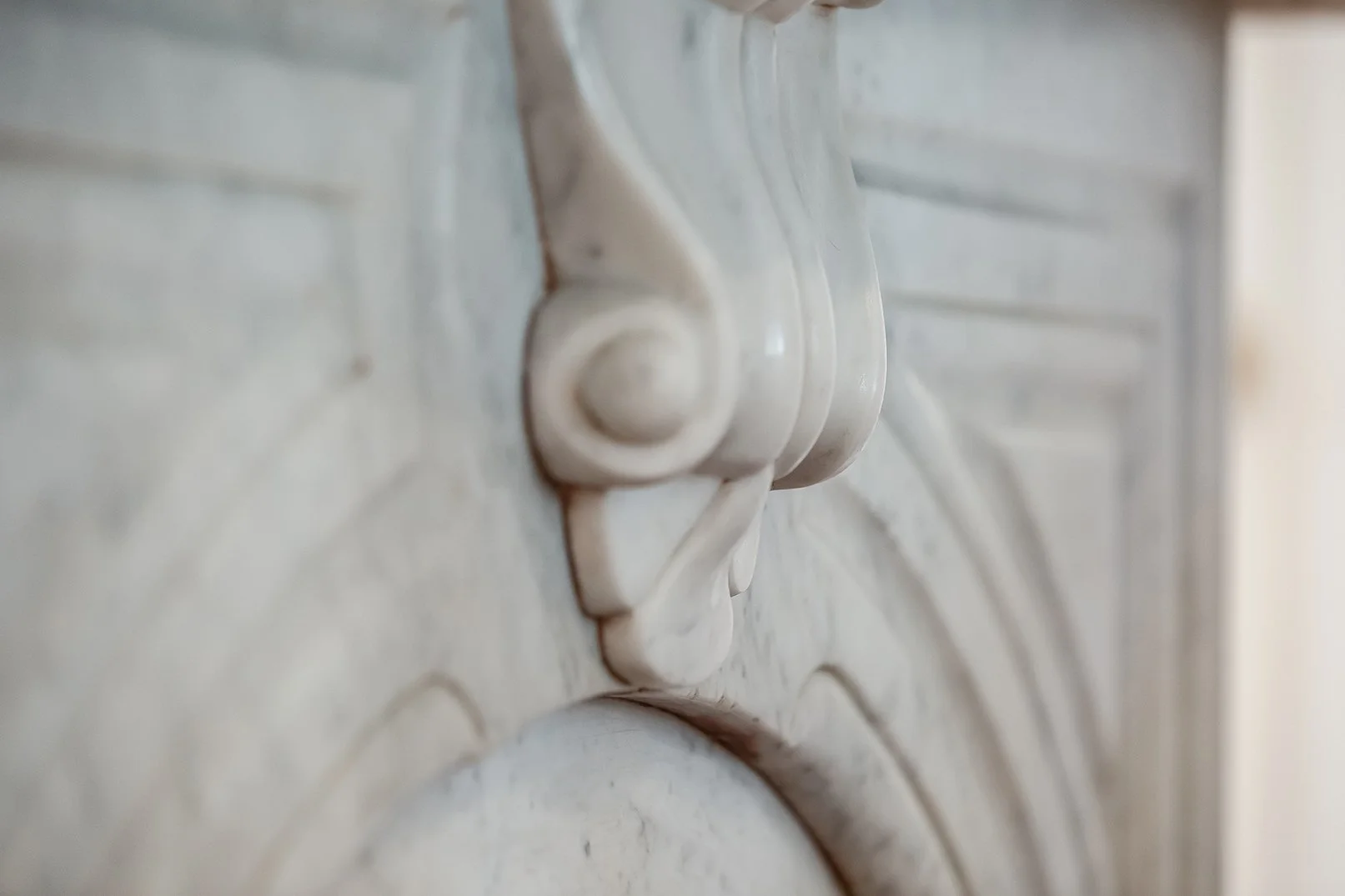 Macro shot of an original, intricately carved white marble fireplace mantel, showcasing the historic period details preserved in this luxury Pacific Heights Victorian.