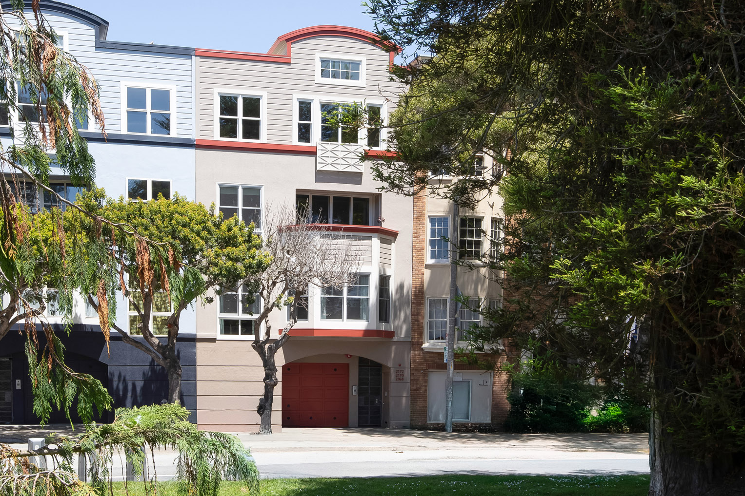 xterior facade of 2172 Fell Street San Francisco condo building with red arched entry, multi-story bay windows, and mature street trees along Fell Street near the Panhandle