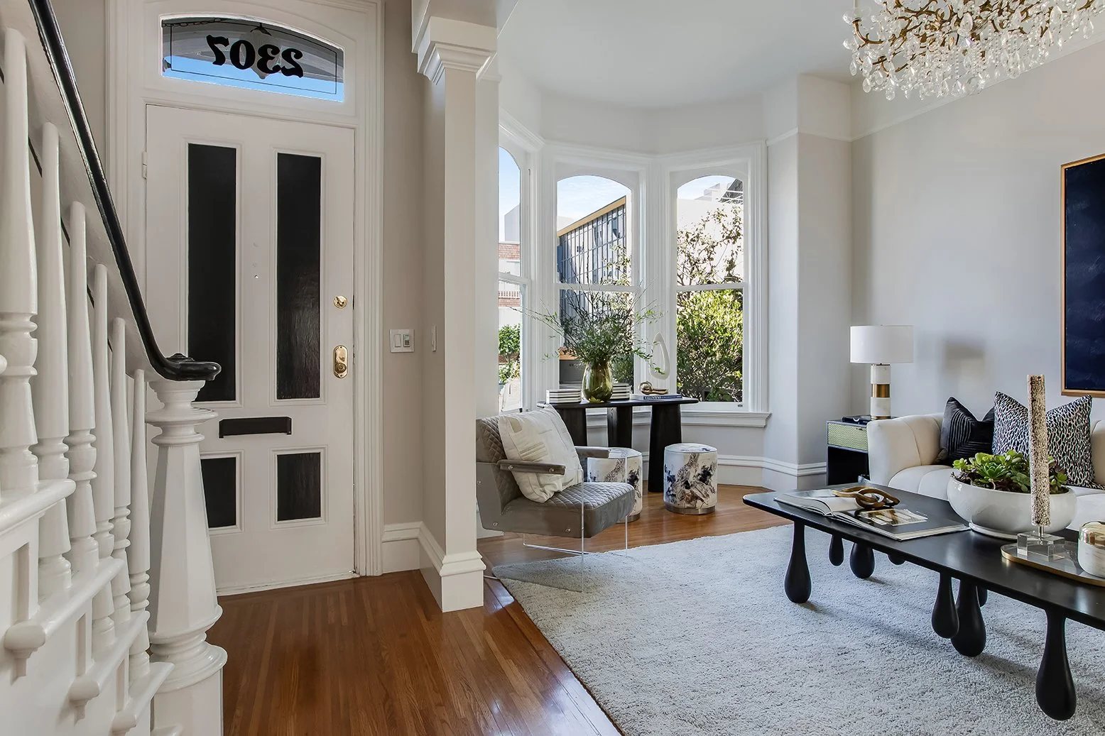 Sun-lit living area with traditional San Francisco bay windows and high ceilings, blending historical architecture with modern interior design.