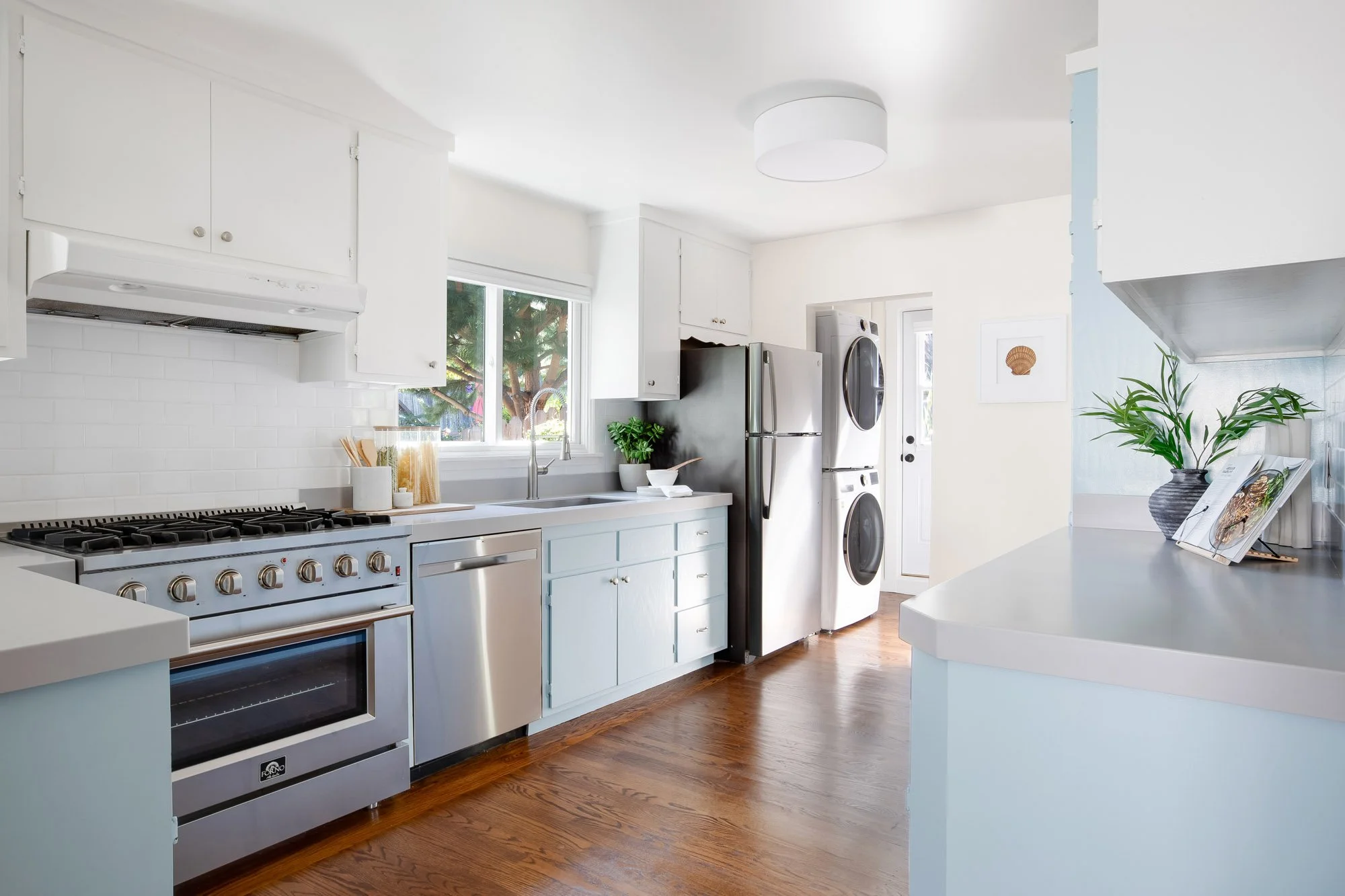 Kitchen at 465 30th Street with a gas range, stainless dishwasher and refrigerator, subway tile backsplash and a window over the sink looking out to the garden