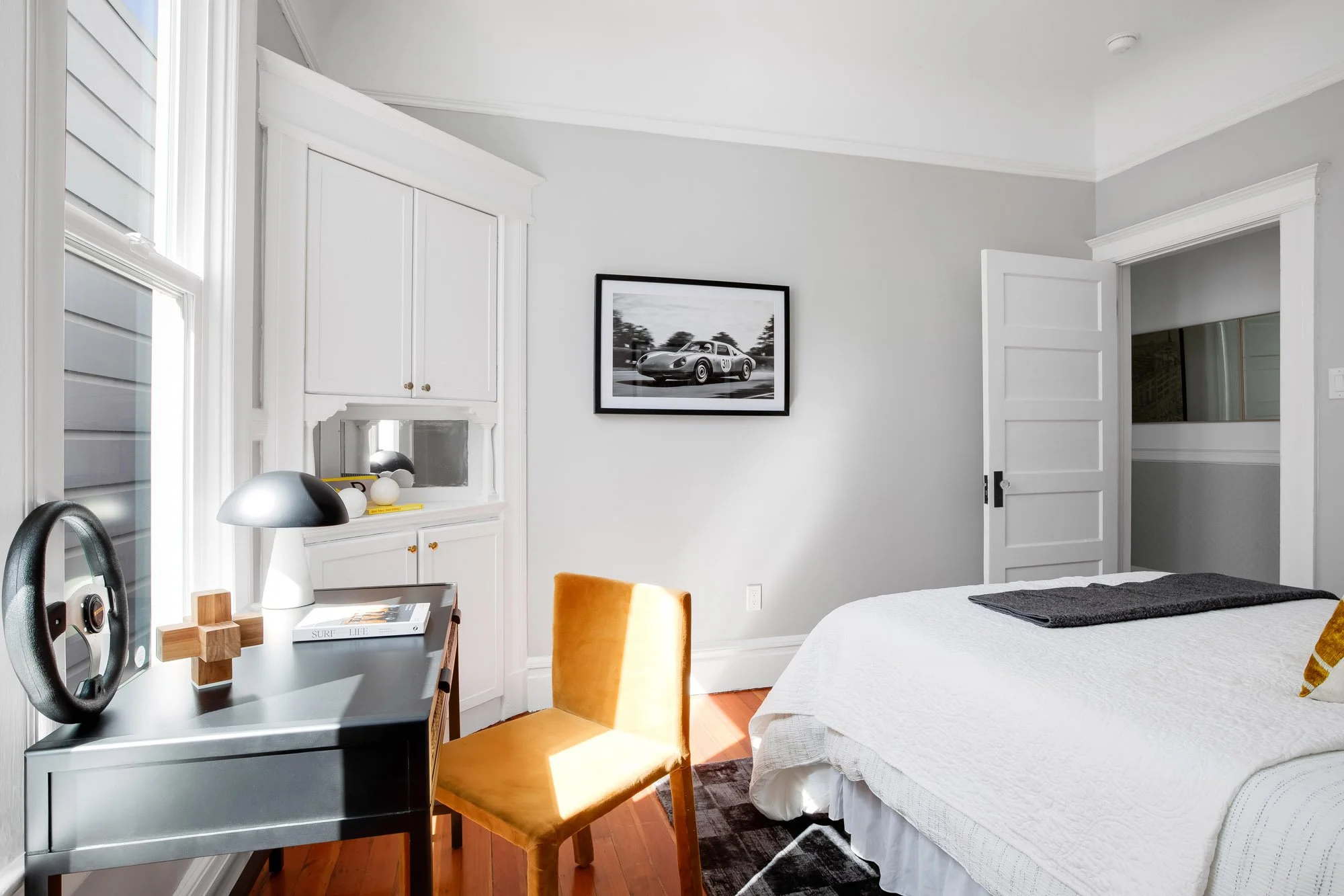 Bedroom desk nook with built-in corner cabinetry and a door open to hallway