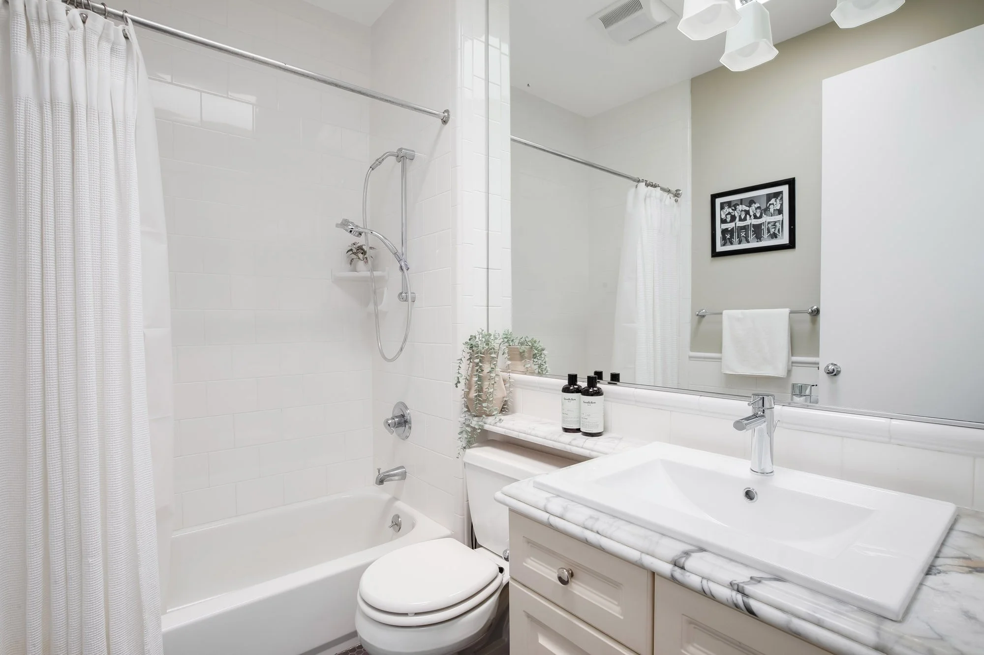Full bathroom at 2172 Fell Street San Francisco with white subway tile shower-tub combo, marble vanity countertop, large wall mirror, chrome fixtures, and crown molding
