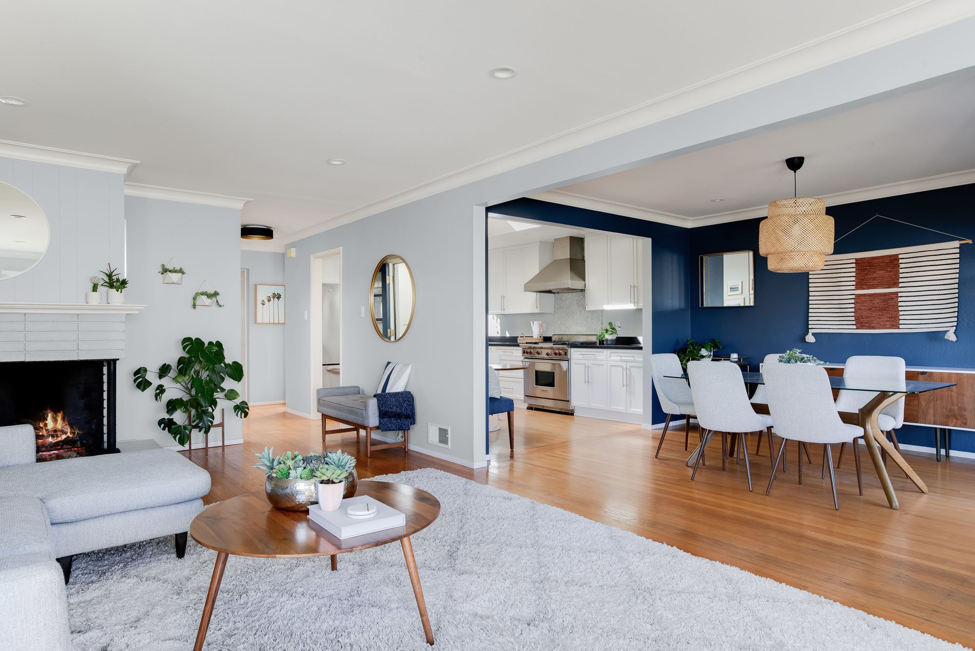 An expansive view of the open-concept main floor, showing the transition from the light gray living room and fireplace to the navy blue dining room and white kitchen.