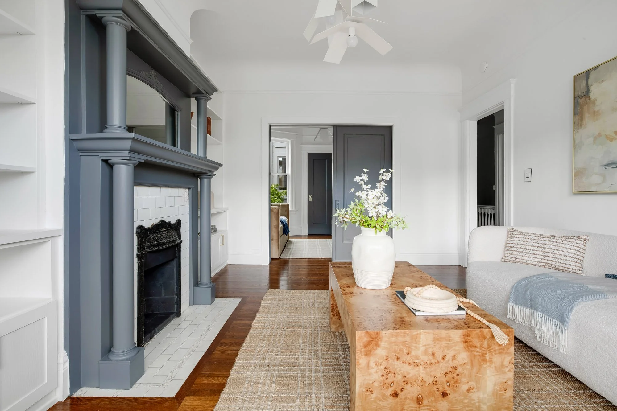 Original Victorian wood-burning fireplace with painted columned mantel, cast iron surround, white subway tile surround, and mirror overmantel flanked by built-in shelving in Presidio Heights flat, San Francisco