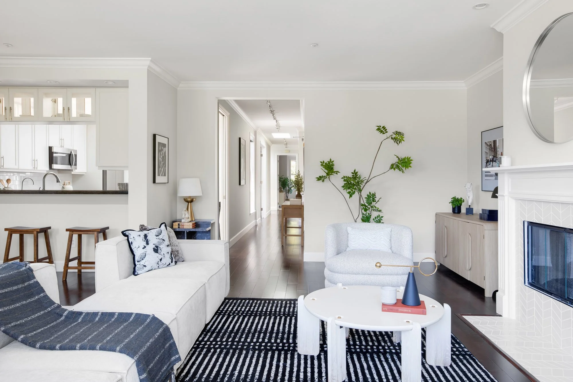 odern living room at 2172 Fell Street San Francisco with white tile fireplace, open hallway, boucle armchair, sculptural white coffee table, and pass-through view into the chef's kitchen