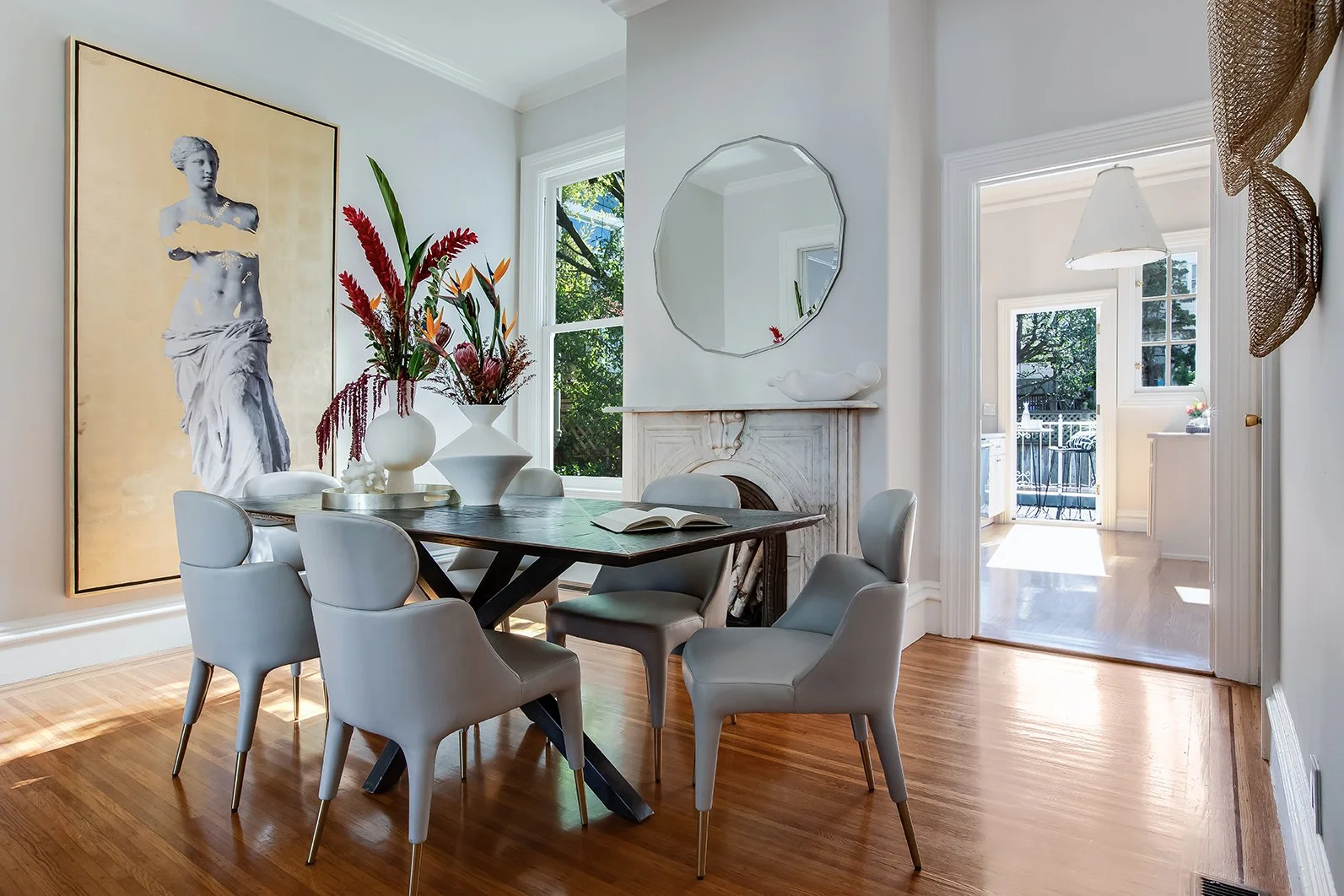 Elegant dining space featuring an original Victorian fireplace mantel and views toward the modernized kitchen, ideal for luxury entertaining.