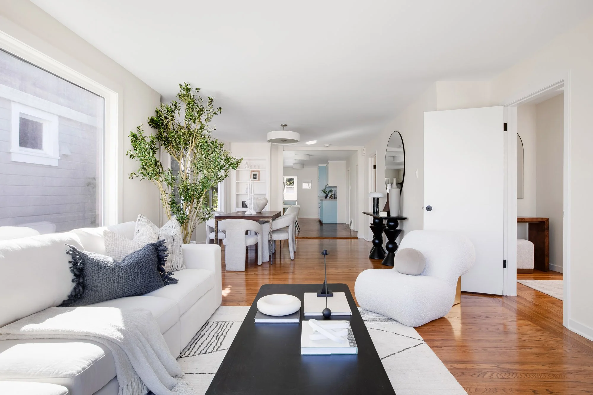 Living room at 465 30th Street with hardwood floors running through to the dining area, built-in shelving and the eat-in kitchen at the back of the house