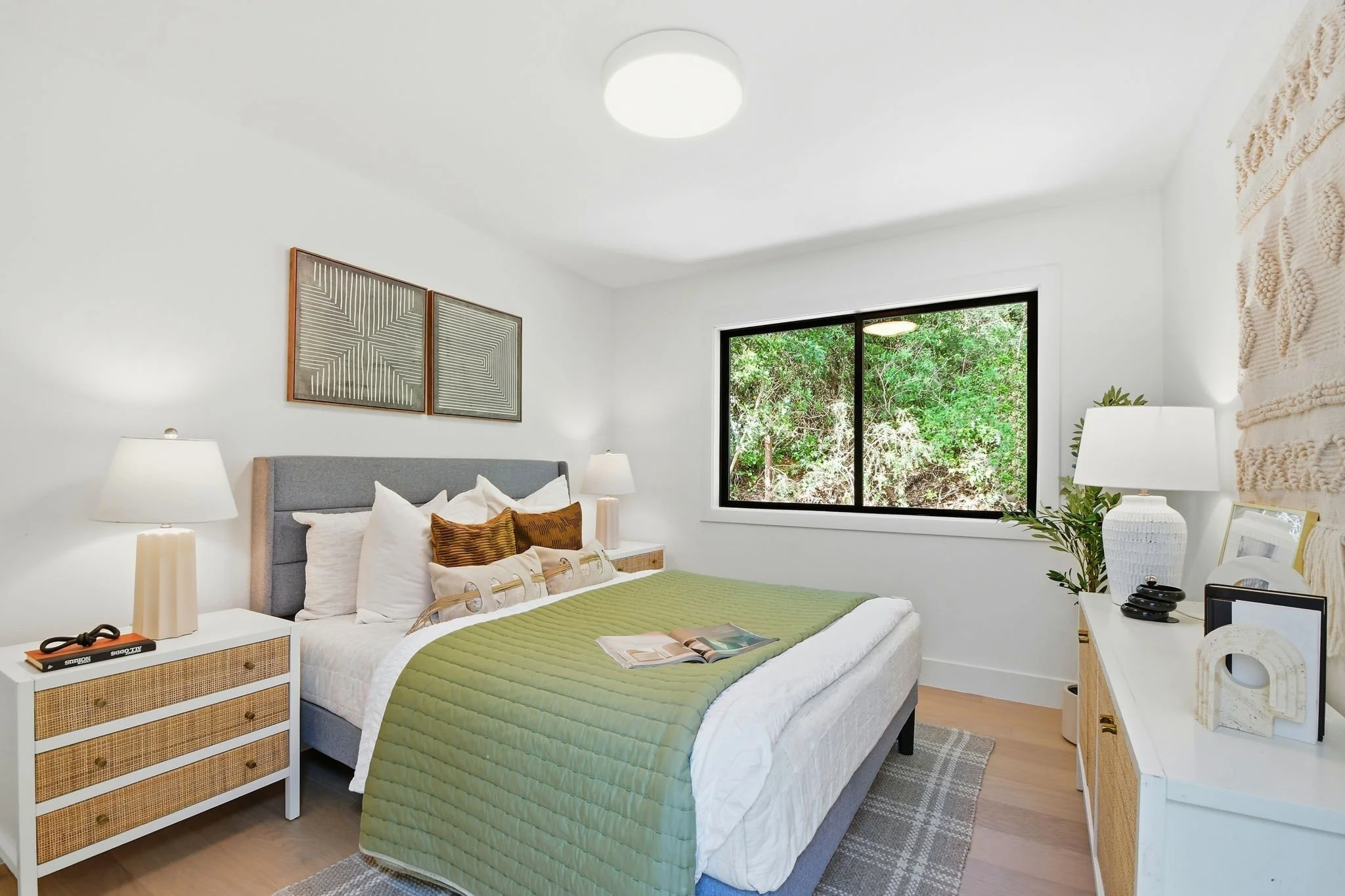 Modern guest bedroom in a luxury Midtown Terrace residence with neutral decor, natural light, and views of the surrounding greenery.