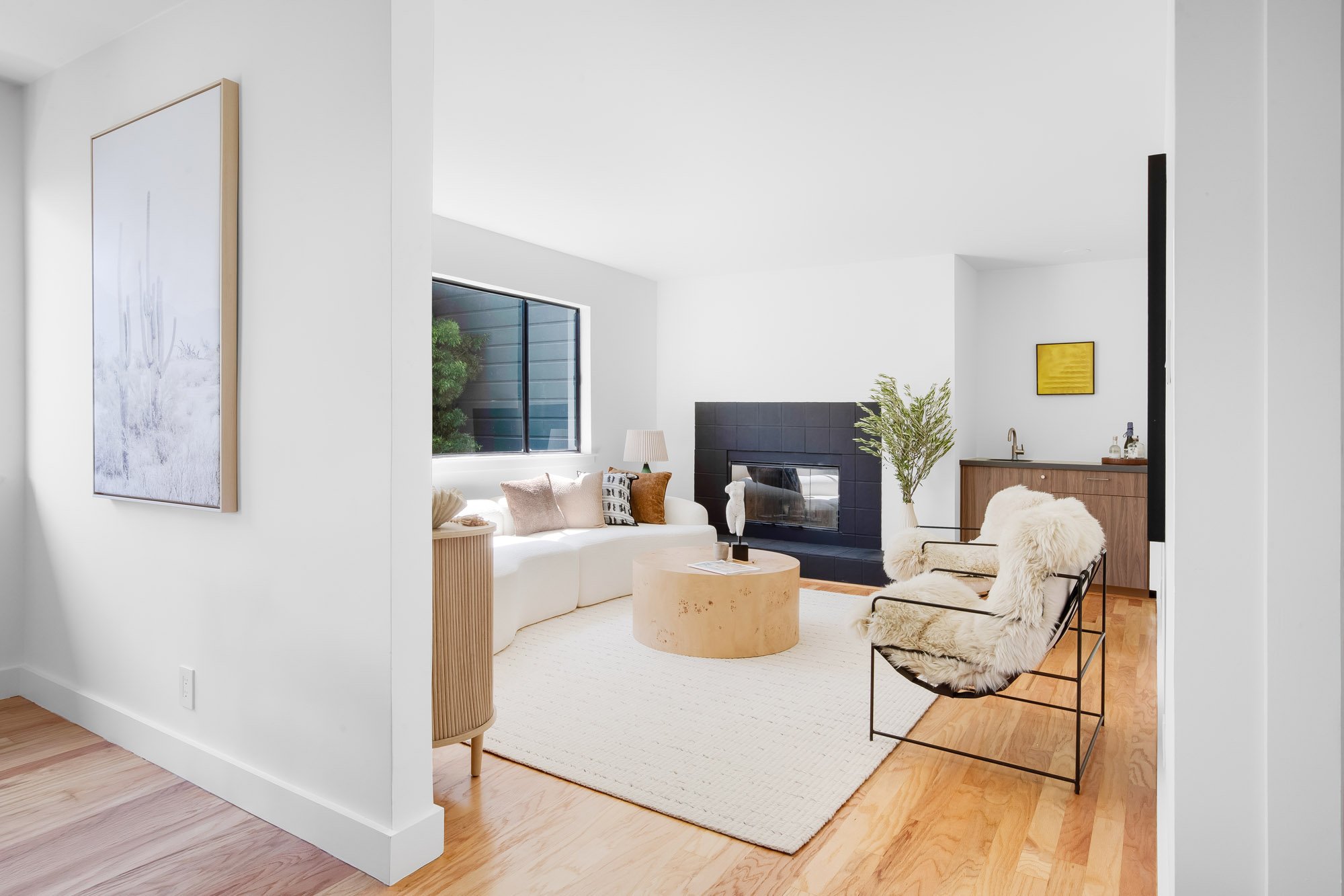 Living and dining rooms at 932 Broderick Street #2 featuring abundant natural light, hardwood floors, and a curved sofa beneath large windows.