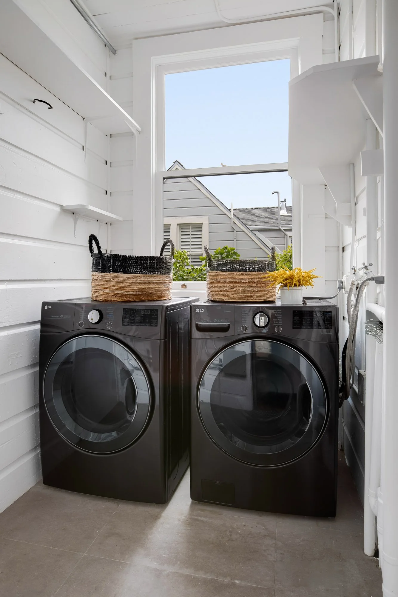 Dedicated laundry room with full-size LG front-load washer and dryer, open shelving, and natural light in luxury Presidio Heights Victorian condo, San Francisco