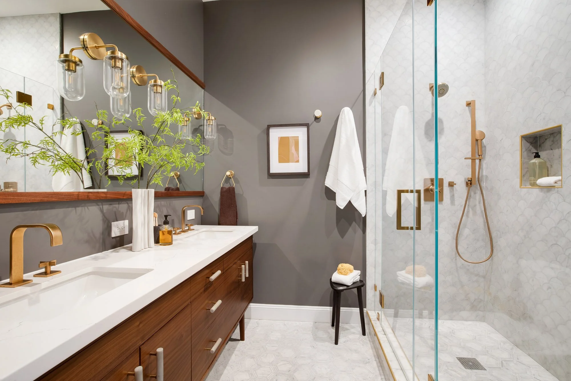 Spa-inspired primary bathroom in San Francisco luxury TIC with walnut floating double vanity, white quartz countertop, brass wall sconces, full-wall mirror, scallop marble tile shower surround, frameless glass enclosure, and brushed gold fixtures
Ima
