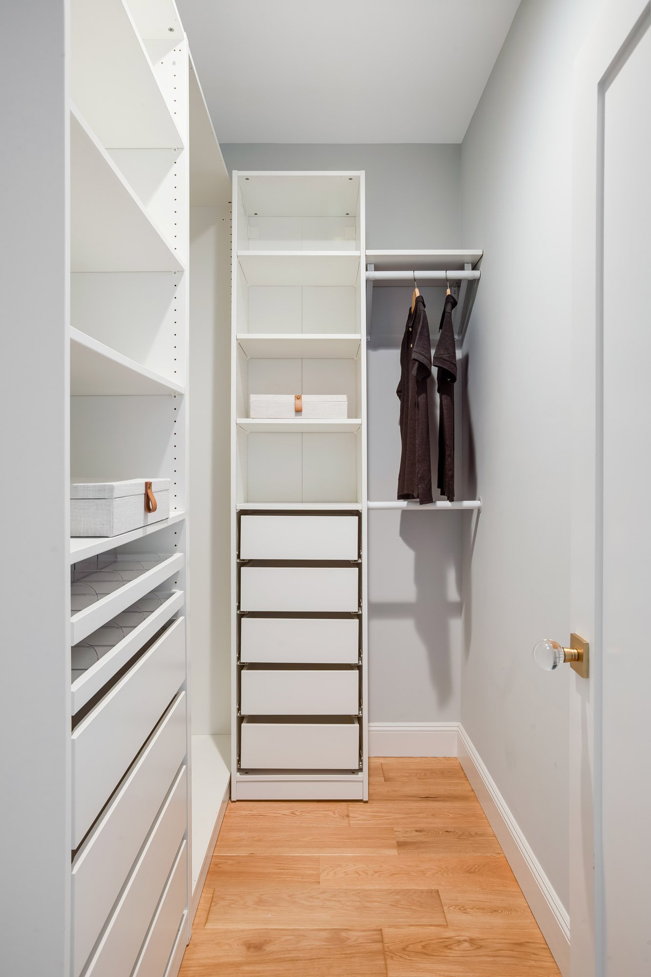 Custom white built-in walk-in closet with floor-to-ceiling shelving, soft-close drawers, double hang rod, and white oak hardwood floors in primary suite at 4545 18th Street San Francisco TIC
