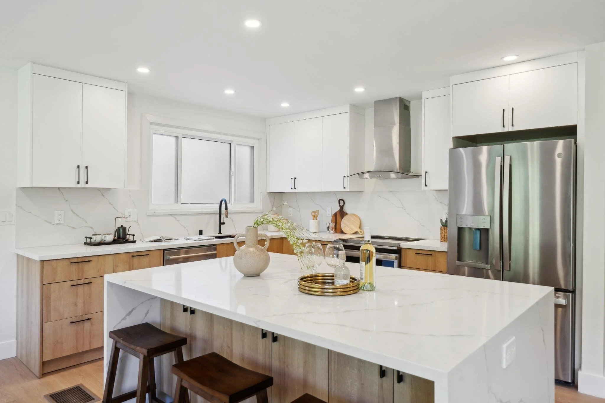 Chef’s kitchen featuring a French door refrigerator, white upper cabinets, light wood lower cabinets, and integrated recessed lighting.