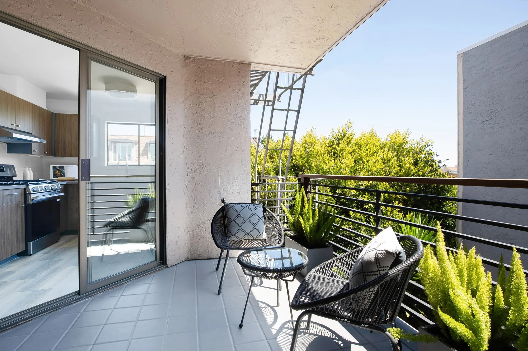 Private balcony off the kitchen at 932 Broderick Street #2 with tiled flooring, potted greenery, and treetop views in NoPa, San Francisco.