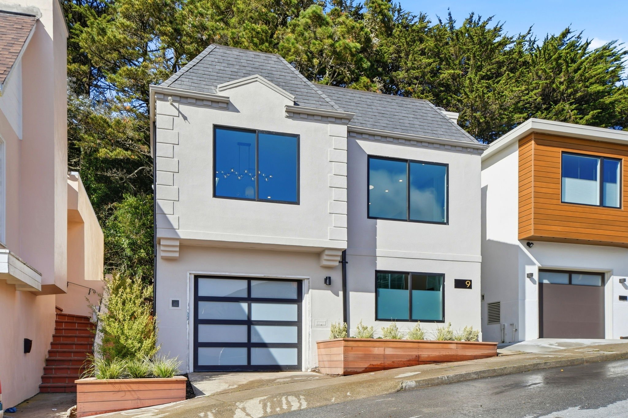 Street-level view of a renovated San Francisco home on a hillside in Midtown Terrace, showcasing a frosted glass garage door and clean architectural lines.