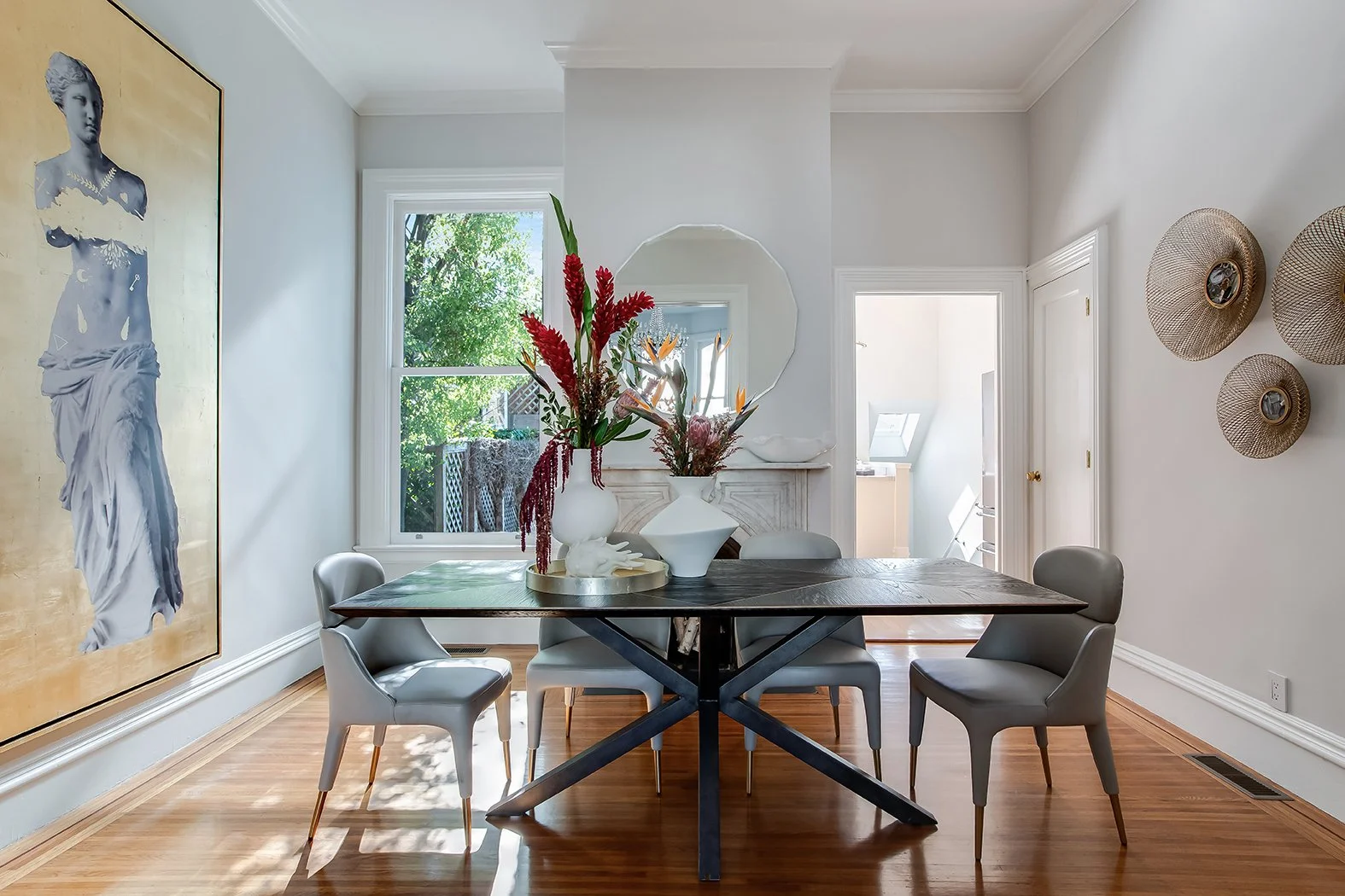 Formal dining room with a white marble fireplace, modern black dining table, and large-scale gold leaf art in a $3M San Francisco home.