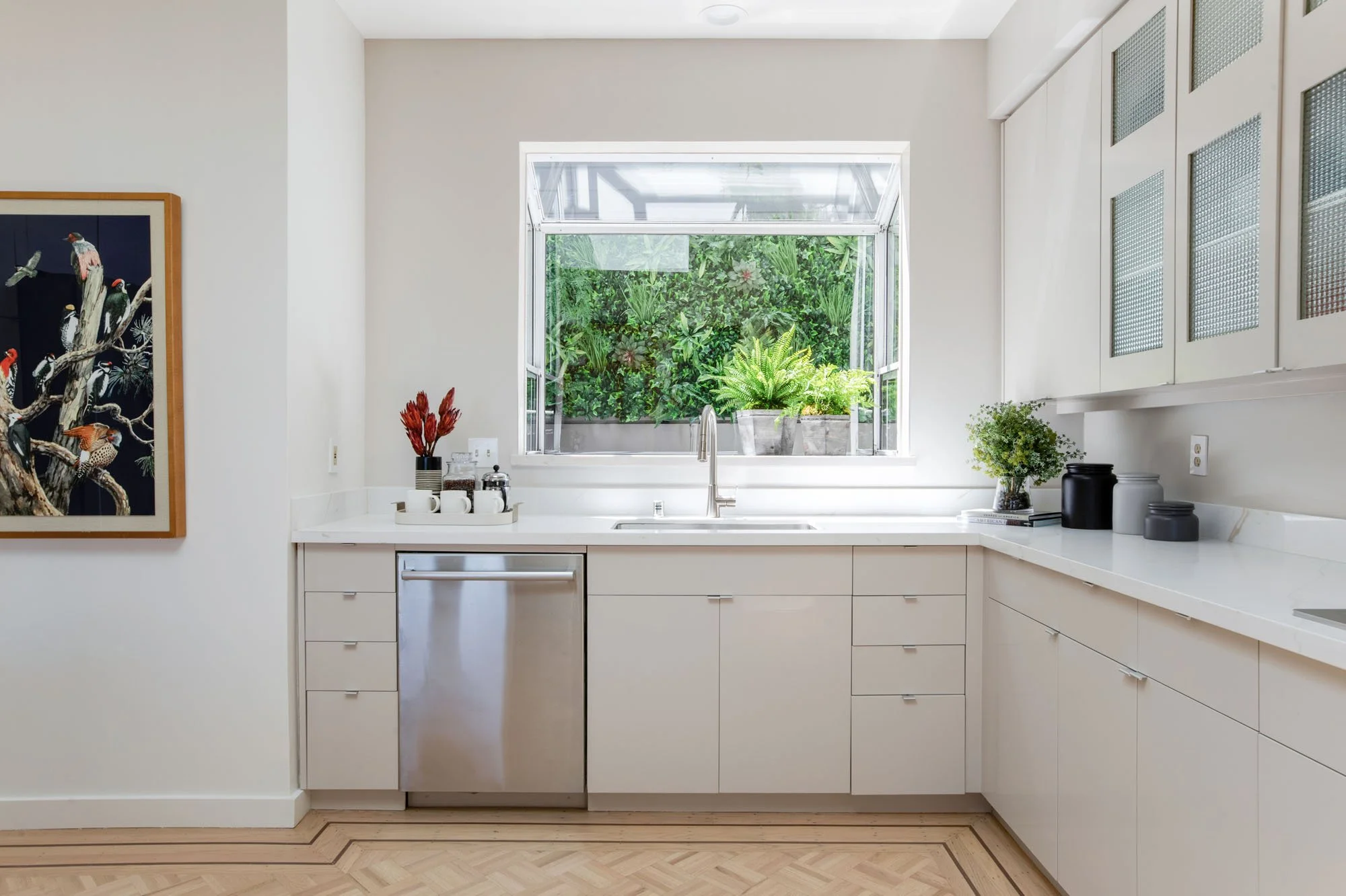 Focused view of a modern kitchen sink area featuring a high-arc faucet and a garden window, highlighting the home's high-end finishes and indoor-outdoor connection.