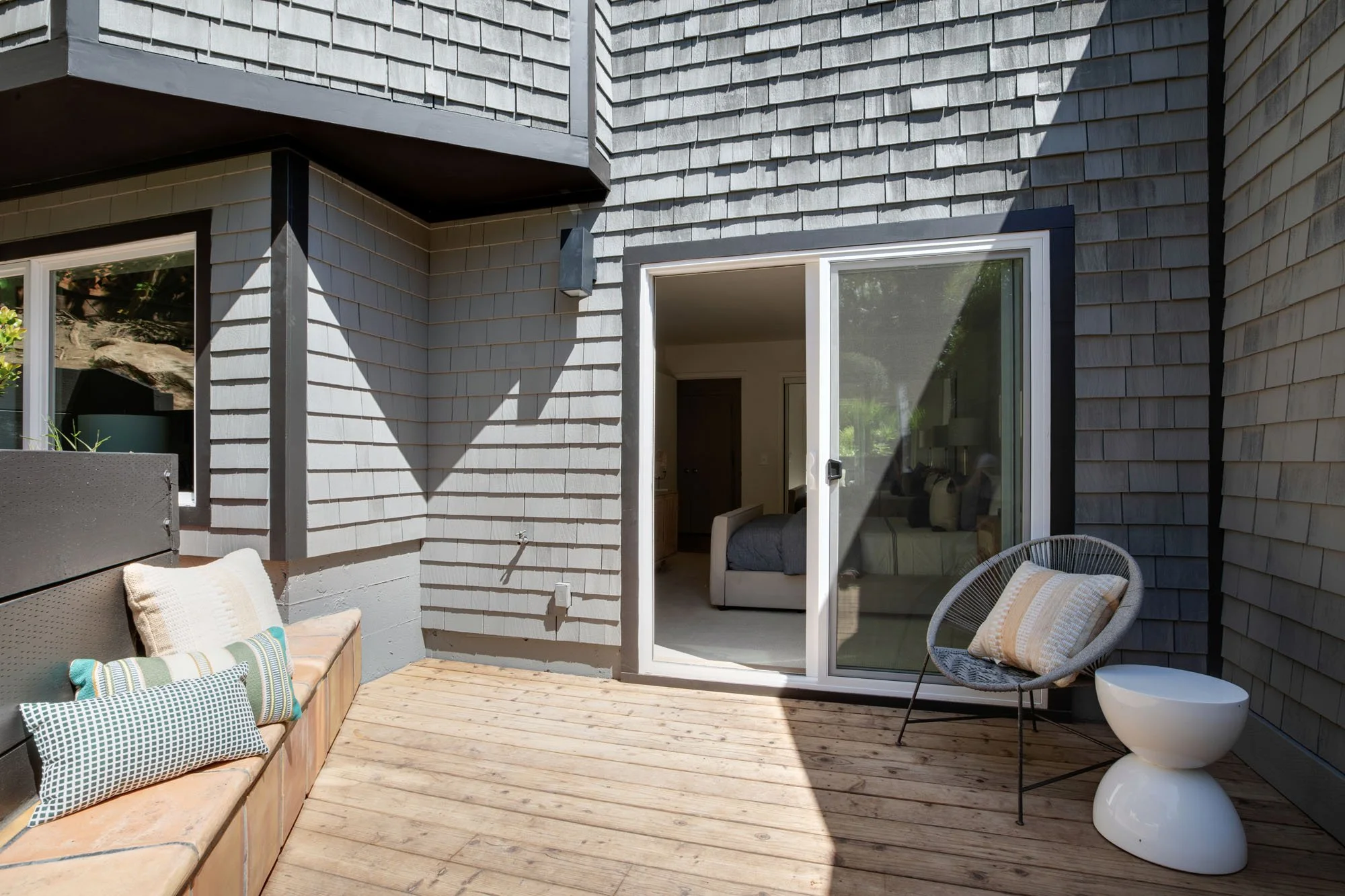 Modern San Francisco home exterior with grey shingle siding and a private walk-out cedar deck, featuring built-in terracotta tile seating and contemporary outdoor furniture.