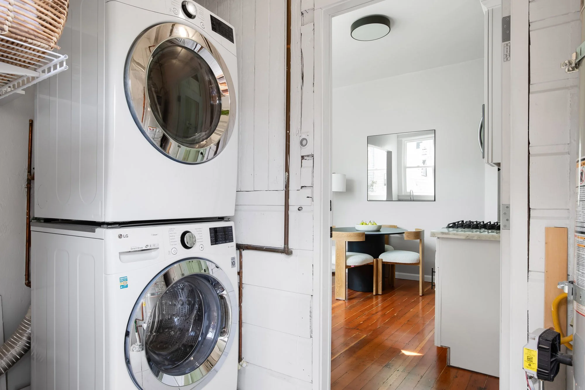Mudroom with stacked washer and dryer, opening to the kitchen and dining area