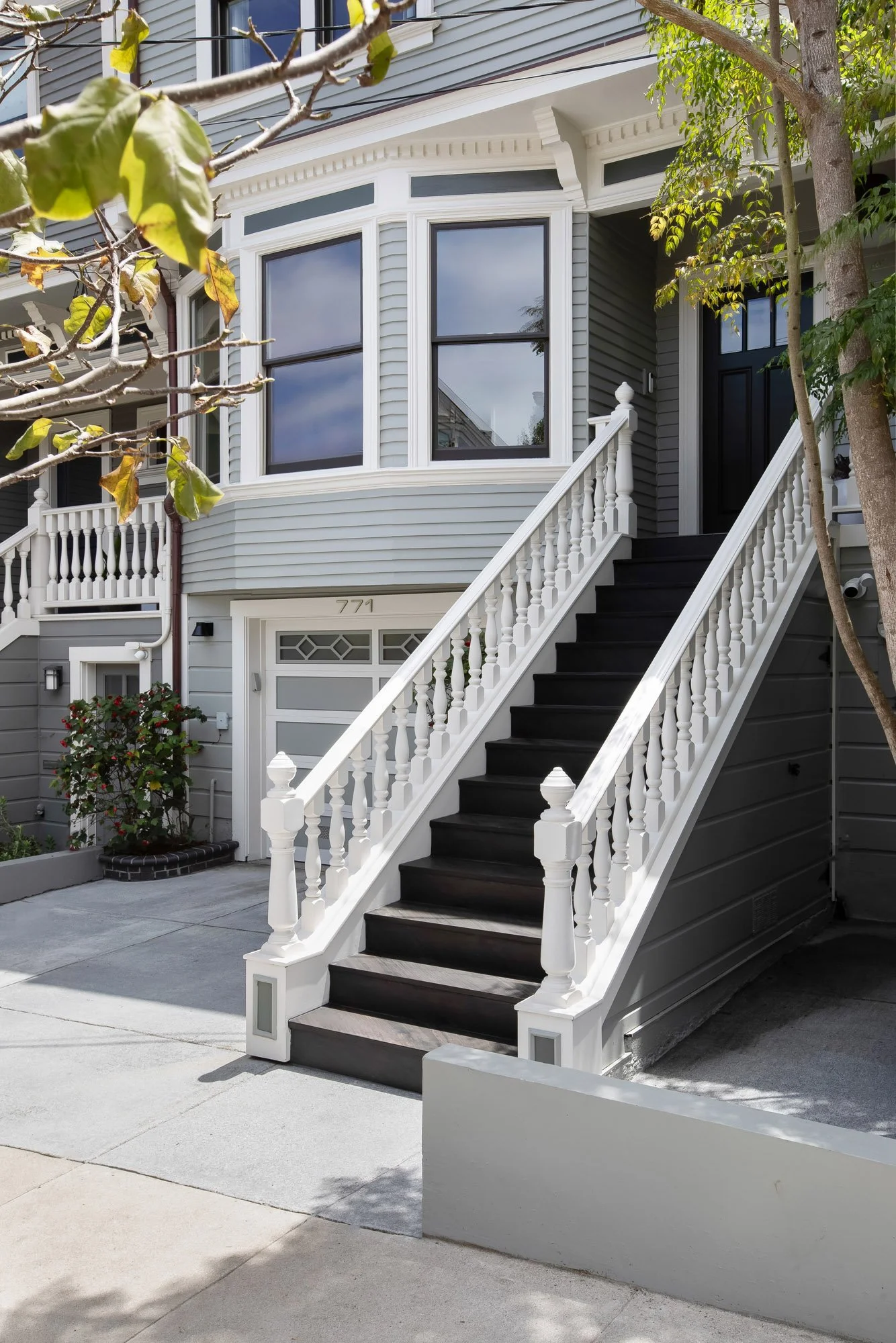 Restored entry staircase at 771 Elizabeth Street in Noe Valley, featuring turned white balusters, dark hardwood treads, original Edwardian millwork, and a black solid-wood front door. #771Elizabeth #NoeValley #SanFranciscoRealEstate #EdwardianDetails