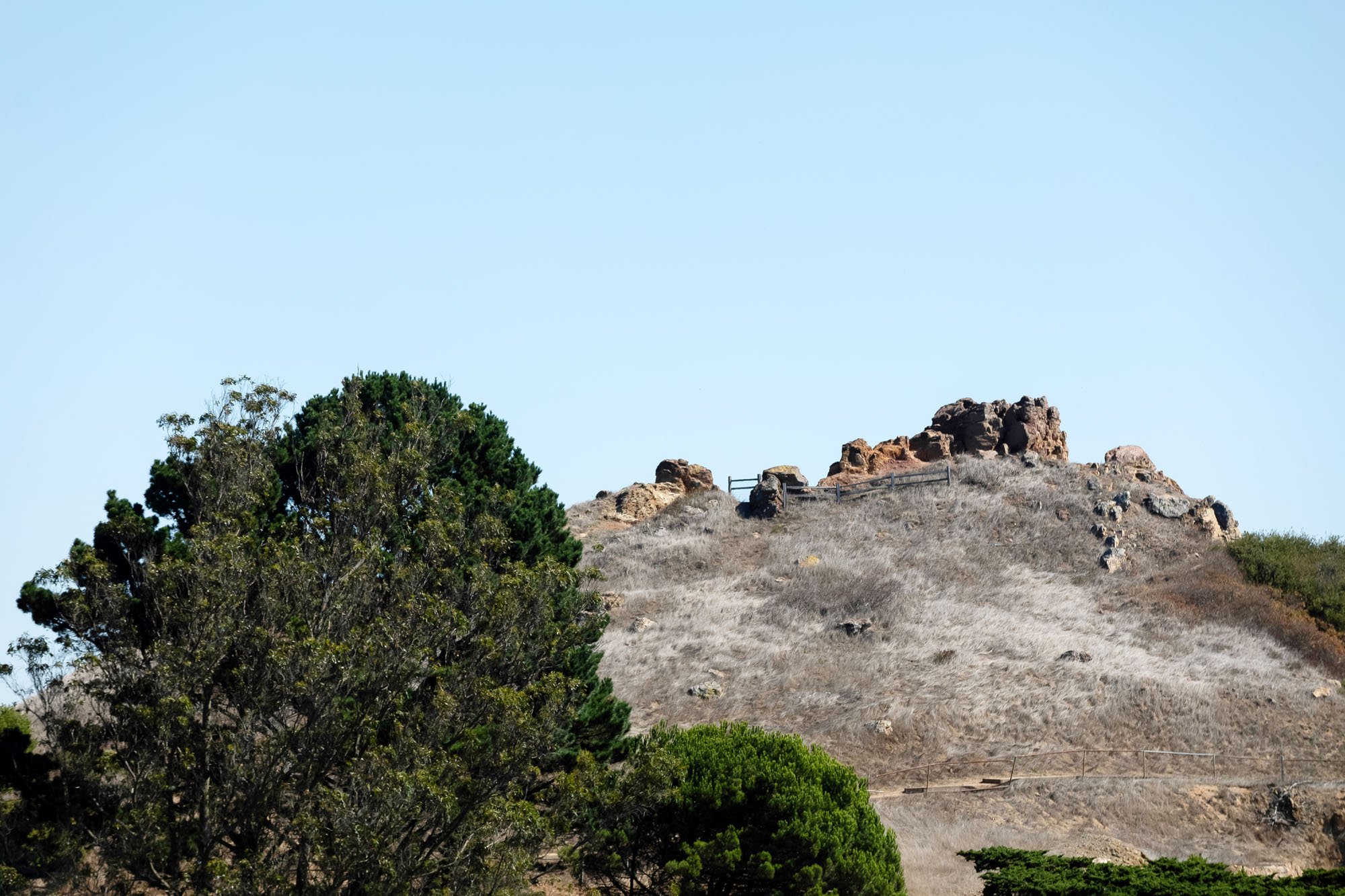 A telephoto shot of the rugged, rocky peak of Corona Heights Park, located just steps away from the property.