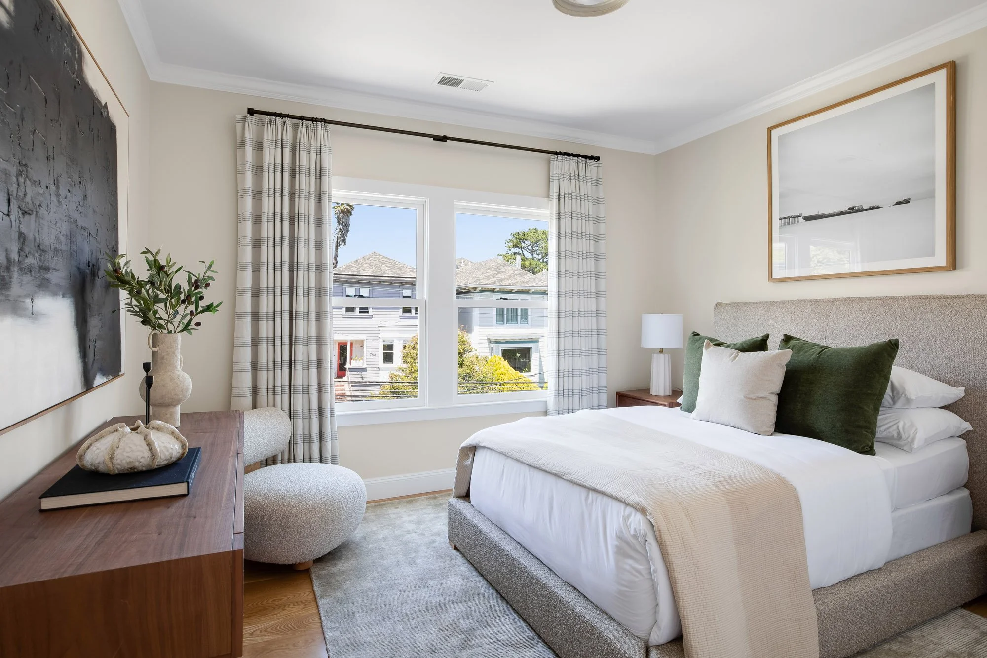 Guest bedroom at 771 Elizabeth Street with an upholstered bed, large-scale art, walnut nightstands, and bay-facing windows overlooking classic Noe Valley rooftops.
