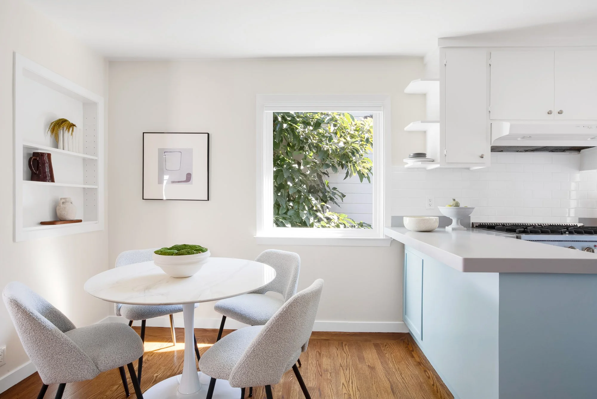 Breakfast nook in an Upper Noe Valley kitchen with a built-in display niche, hardwood floors and a garden-view window
