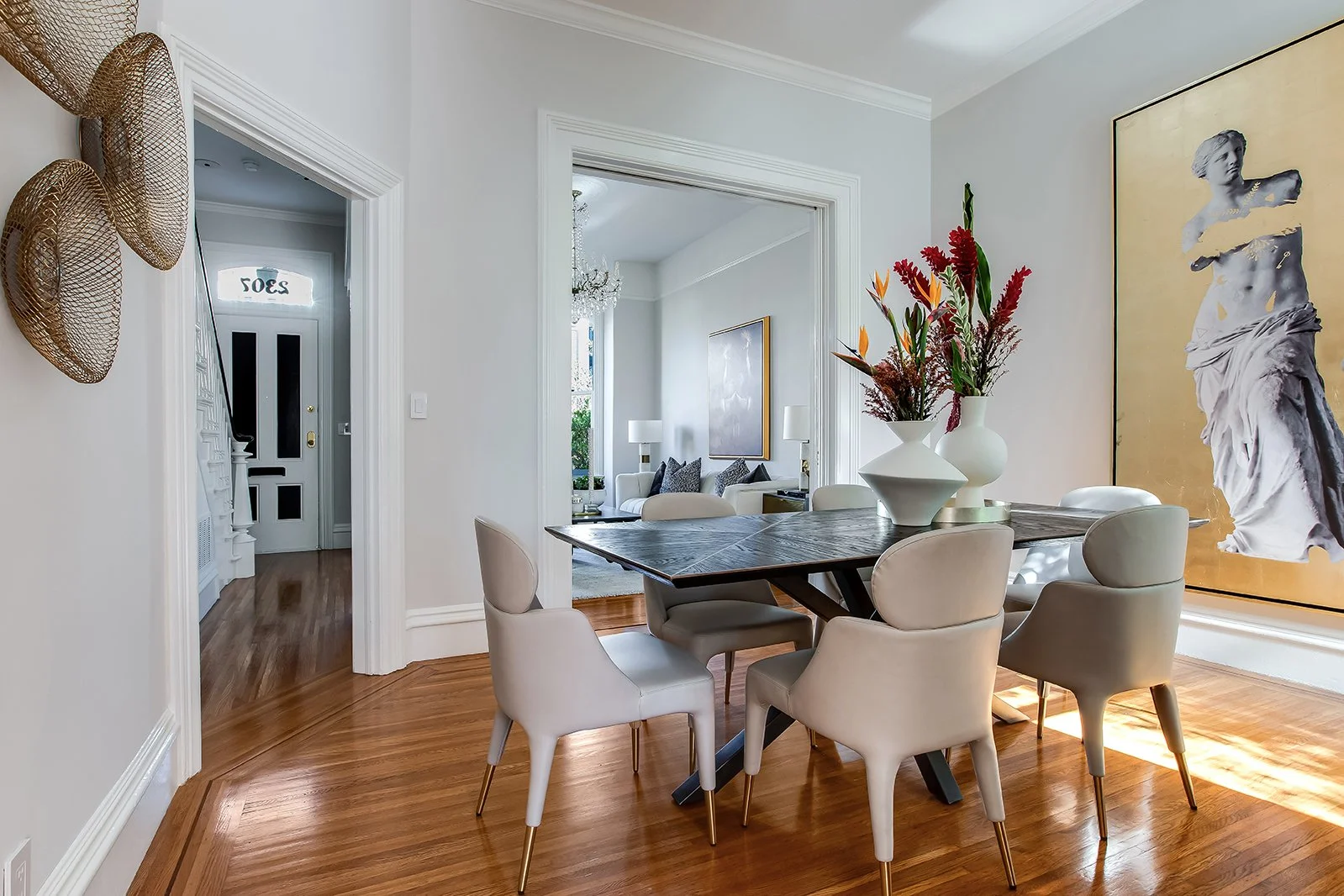Elegant formal dining room in a San Francisco Victorian, featuring wide-plank hardwood floors and views into a sun-drenched living area.