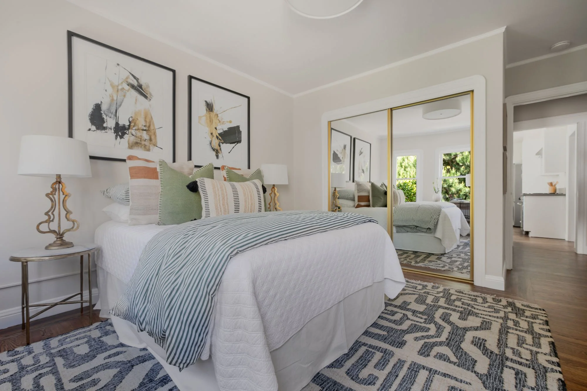 Spacious bedroom featuring gold-framed mirrored closet doors that reflect the light and modern interior design of this Mission District residence.