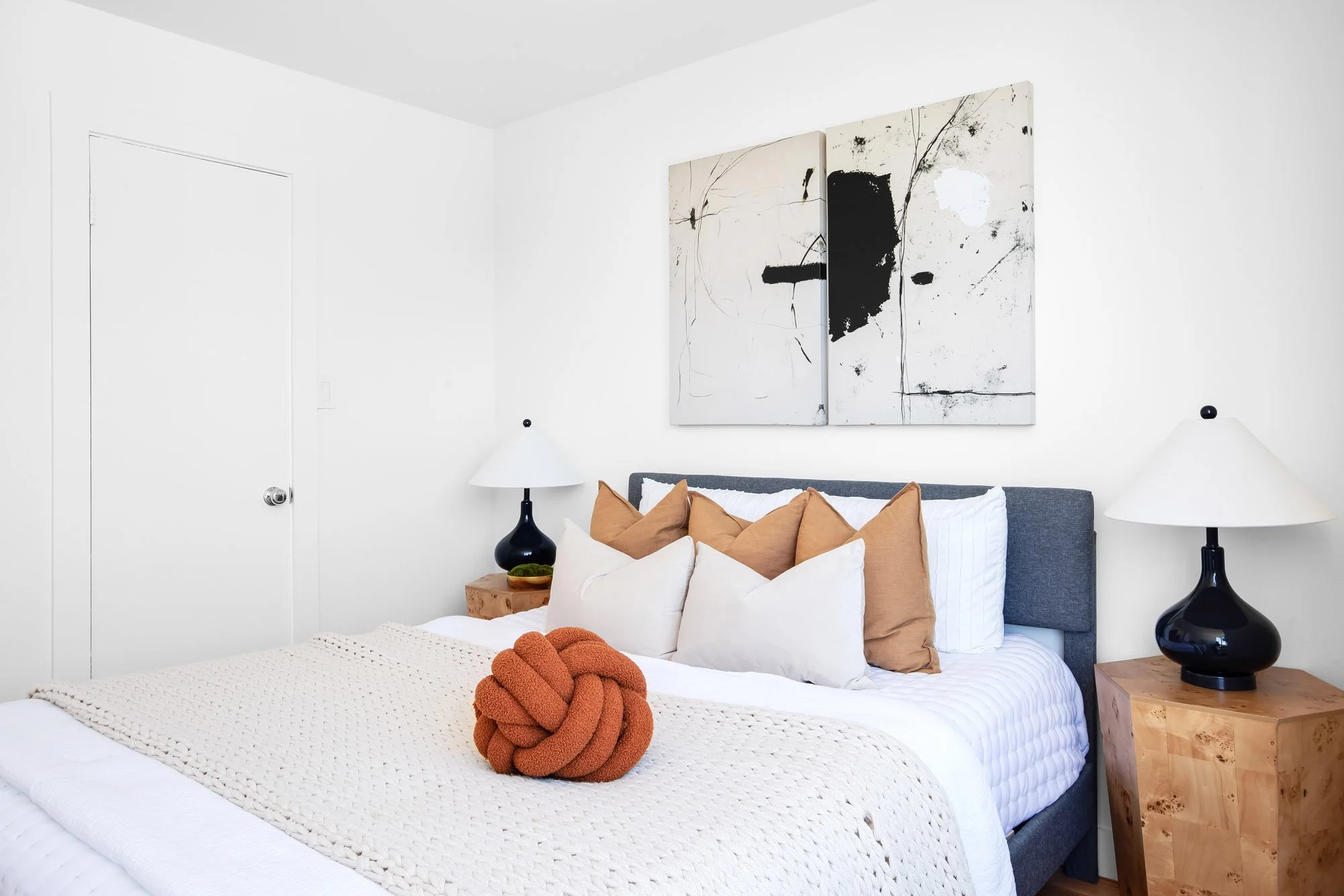 Second bedroom at 932 Broderick Street #2 with a blue upholstered bed, abstract artwork, and burl wood nightstands in NoPa, San Francisco.