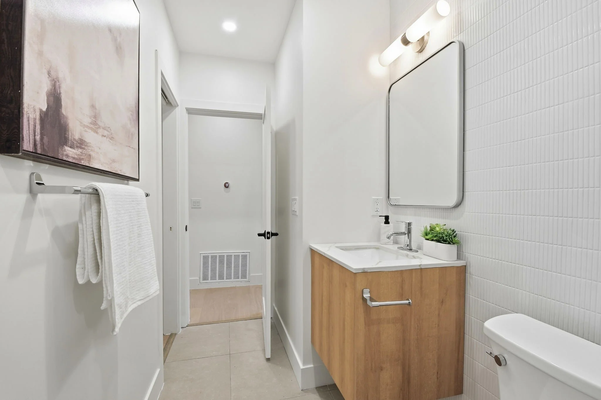Bright, renovated secondary bathroom in Midtown Terrace with white tile walls, wood accents, and modern black fixtures.