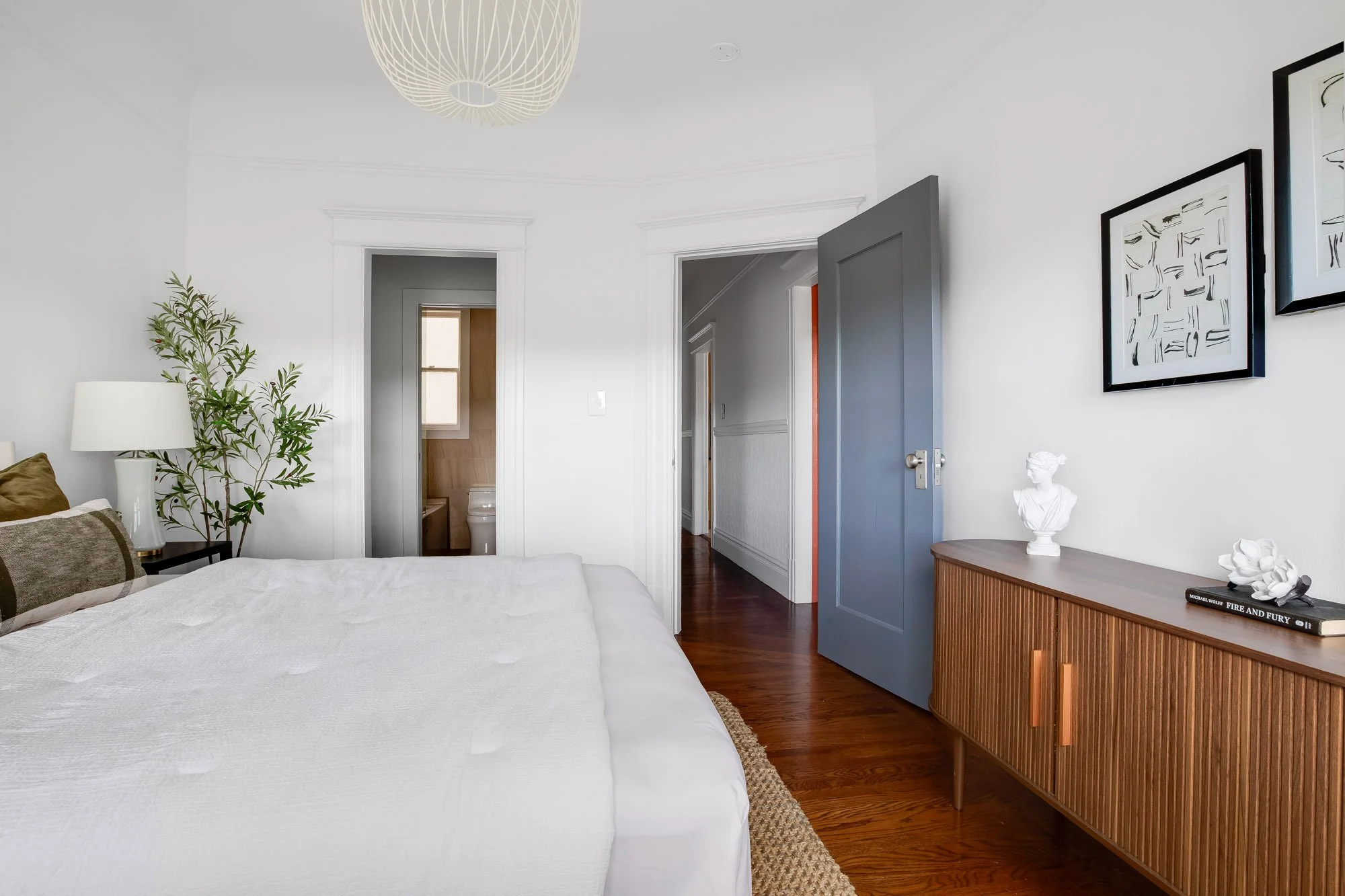 Primary bedroom with original hardwood floors, crown molding, and direct access to renovated ensuite bathroom in luxury Presidio Heights Victorian condo, San Francisco