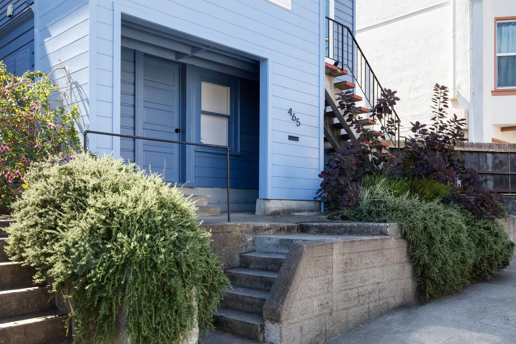 Street-level entry at 465 30th Street with a recessed door to the finished lower level, concrete steps and drought-tolerant front plantings