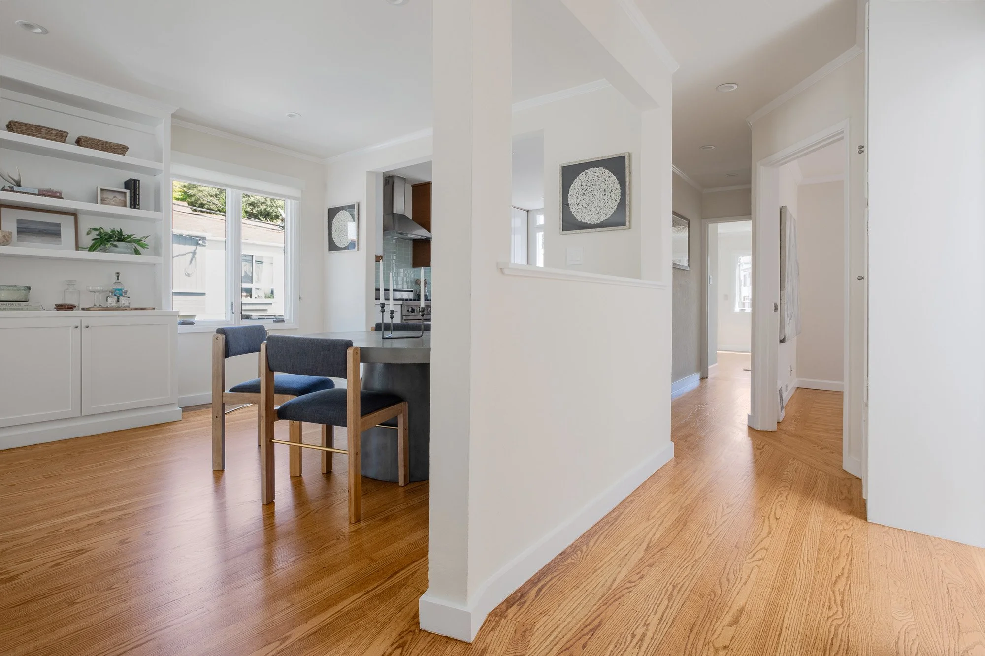Spacious hallway with polished hardwood floors and an open view into the modern dining area and kitchen.