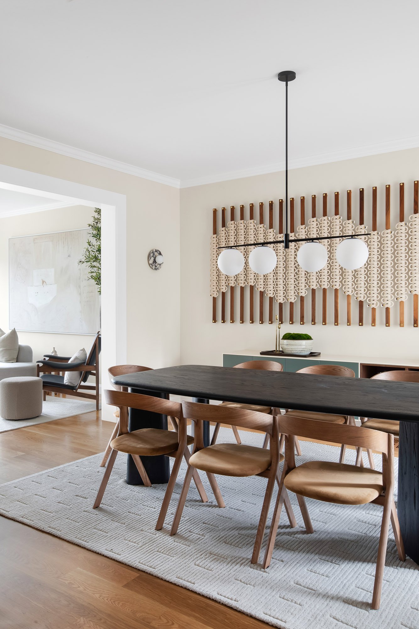 Dining room at 771 Elizabeth Street in Noe Valley with a wall-anchored Windy Chien "Hitching Post" cordage installation, four-globe linear chandelier, black oak table, and an open sightline to the adjoining living room. 