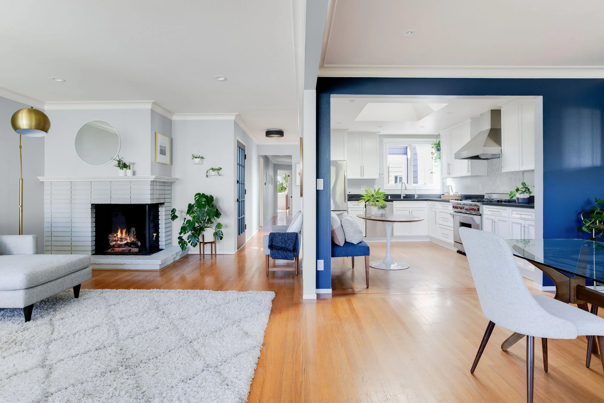 View from the dining room into the bright, renovated kitchen, featuring white cabinetry, a large skylight, and a blue built-in breakfast banquet.