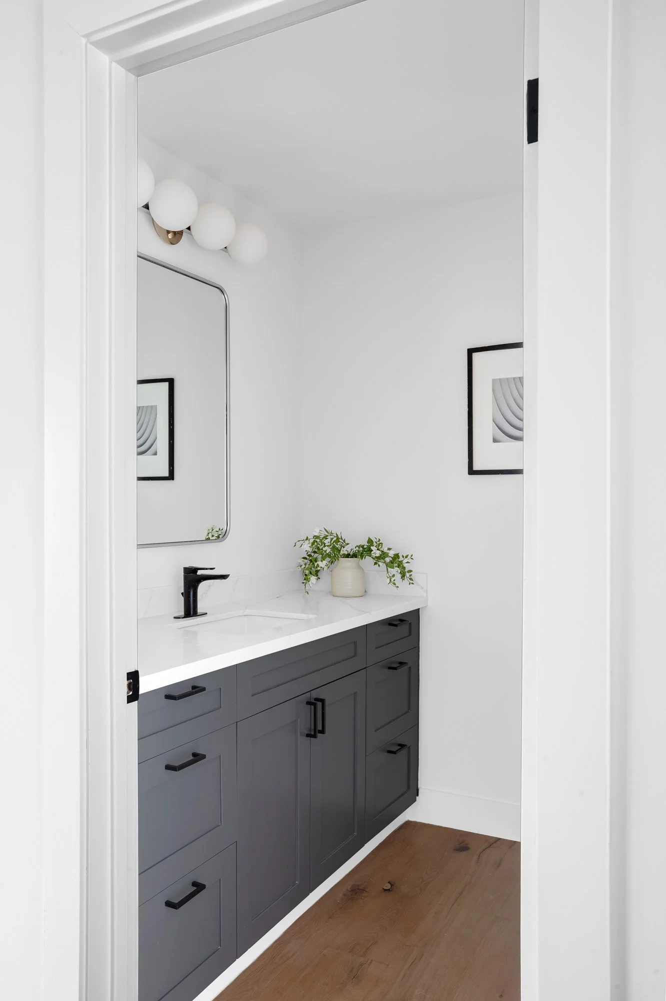 Renovated hallway bathroom at 75 Aloha Avenue in Golden Gate Heights, with a charcoal vanity, quartz counter, and a globe sconce.