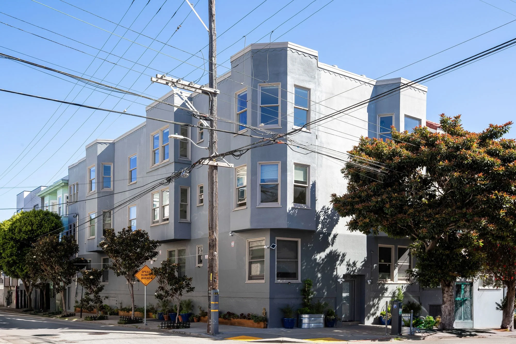 Exterior corner view of a modern grey multi-unit residential building at 3426 19th Street in San Francisco with classic bay windows.